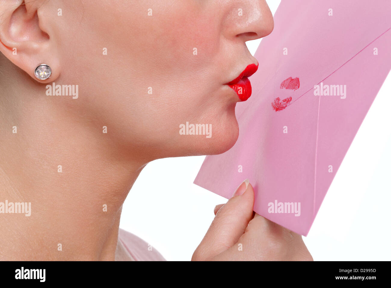 Donna che indossa un rossetto rosso baciare una busta - sigillato con un affettuoso bacio o SWALK per brevi. Foto Stock