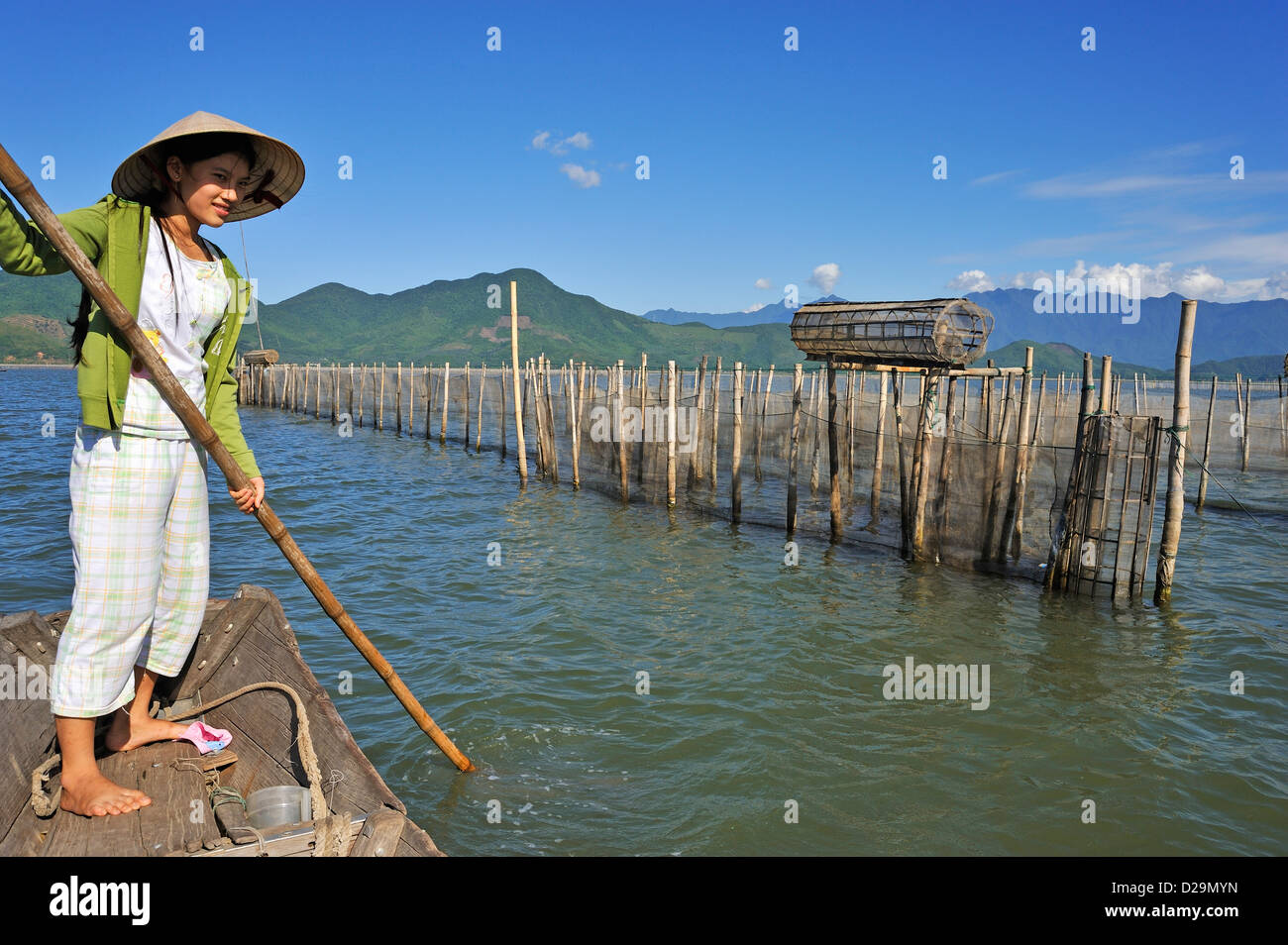 Fisherwoman sulla barca da pesca le trappole, Phu Loc lago / laguna, Vietnam Foto Stock