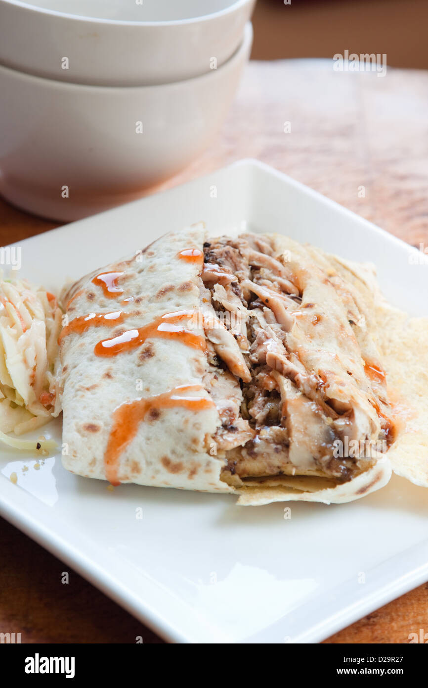 Lo stile caraibico pollo jerk servita nei tradizionali roti e spruzzata con dolci salsa calda. Servito con un lato della coleslaw. Foto Stock