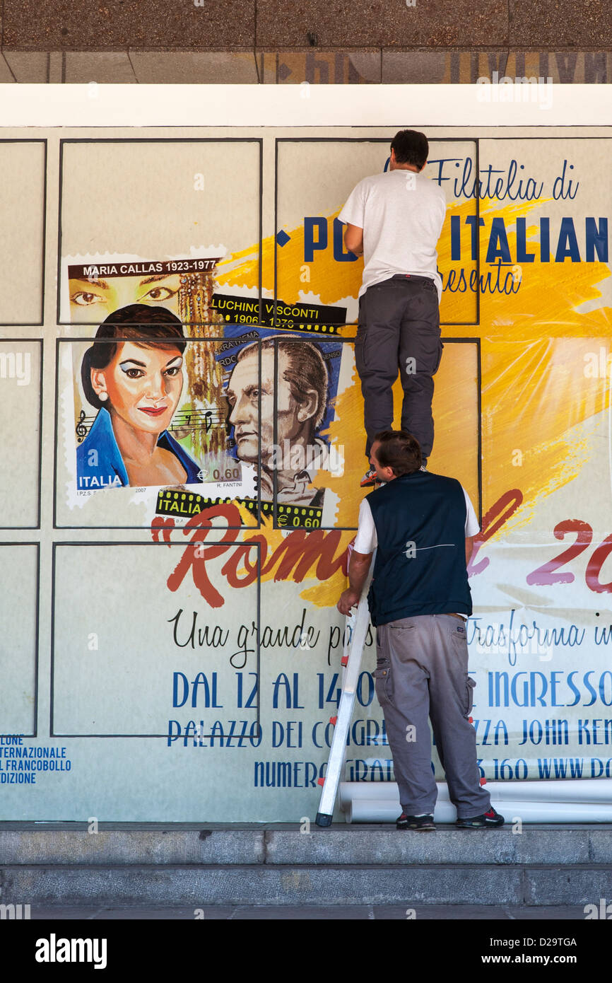 Operai italiani appeso un poster del film a Roma, Italia Foto Stock