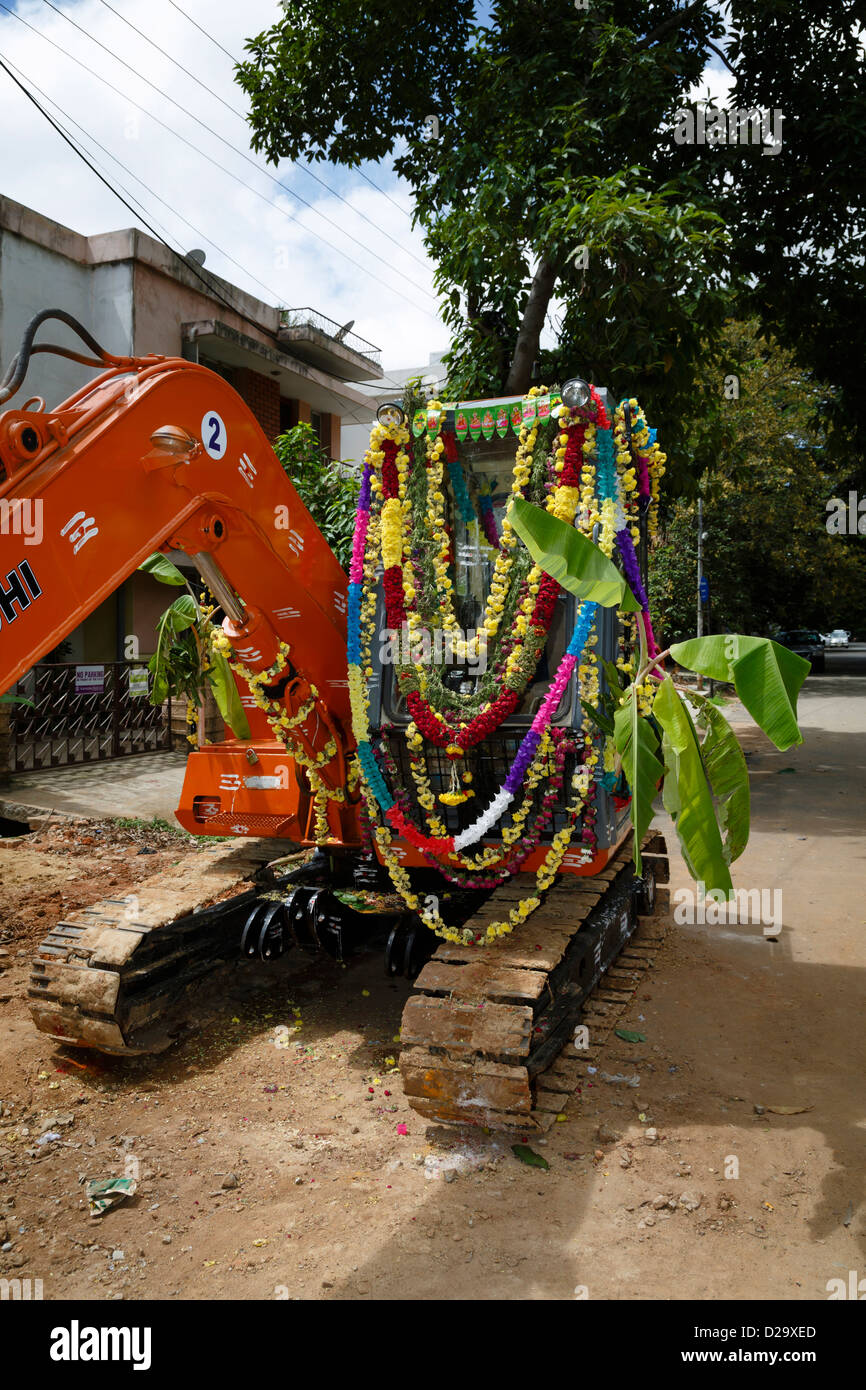 Un escavatore è ornata con foglie di banano e fiori per il festival indù Dussehra, Bangalore, India Foto Stock