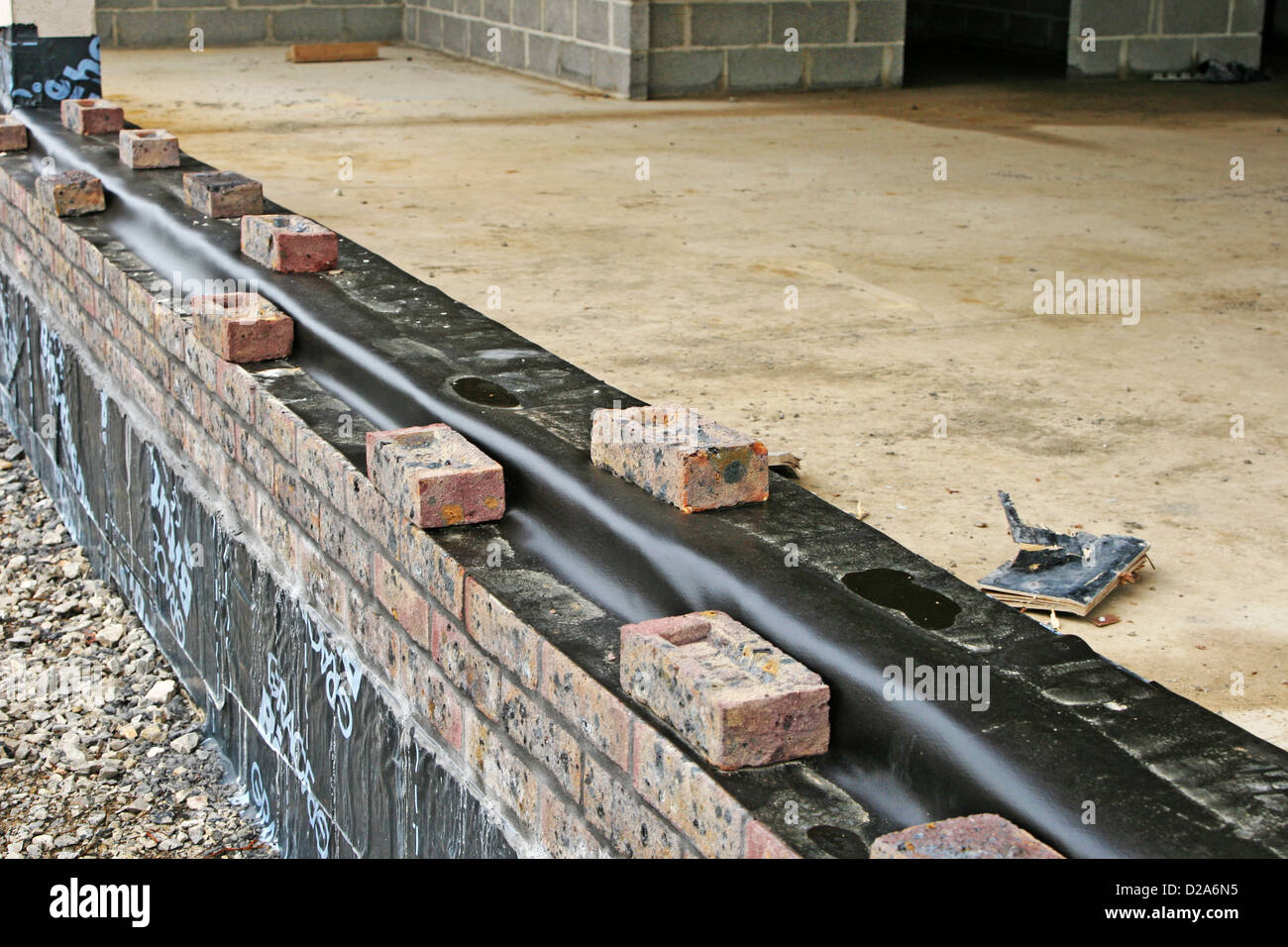 La prima fila di mattoni fino a umido lo strato di prova per la costruzione di una nuova scuola o in ufficio Foto Stock