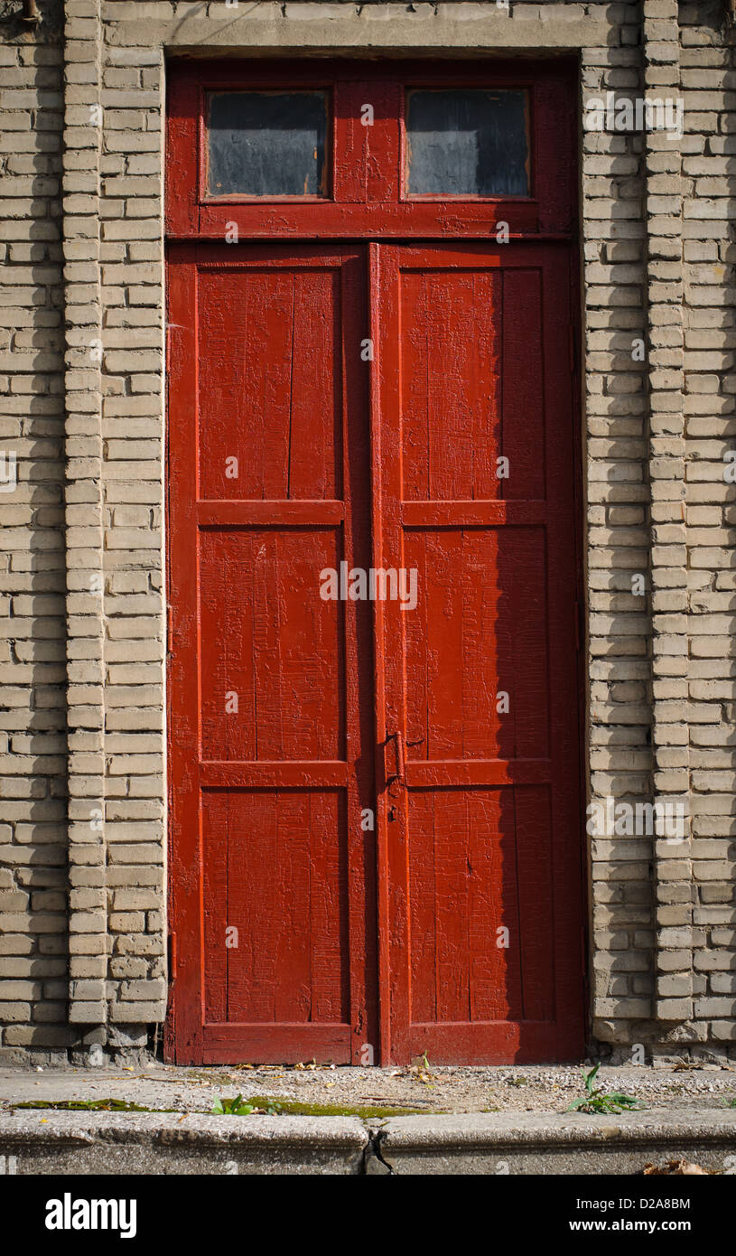 Una vecchia porta di legno rotto con vernice rossa e grunge Foto Stock