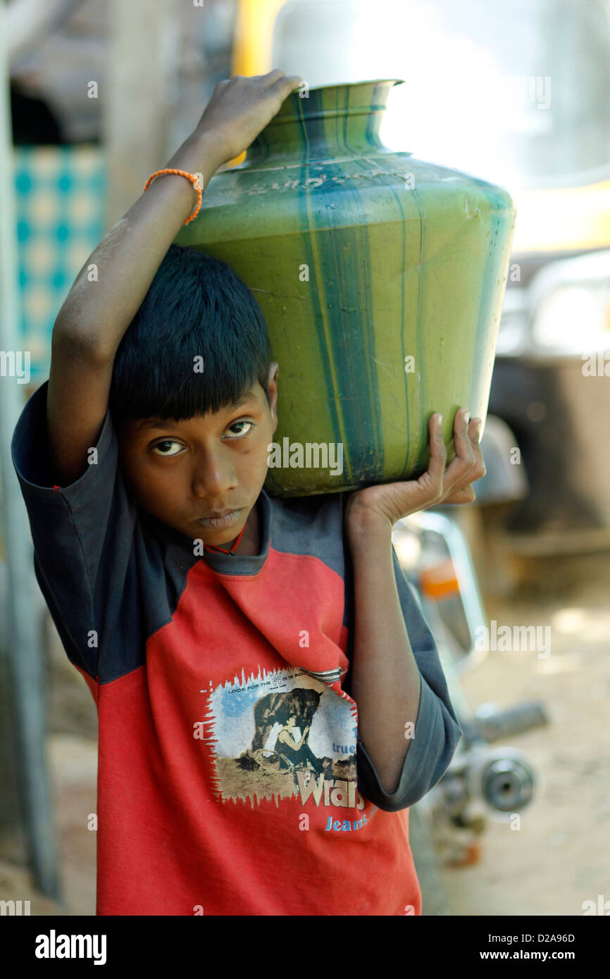 Ritratto di un ragazzo che trasportano l'acqua da un punto comune per la sua casa rurale nella periferia di Bangalore, India Foto Stock