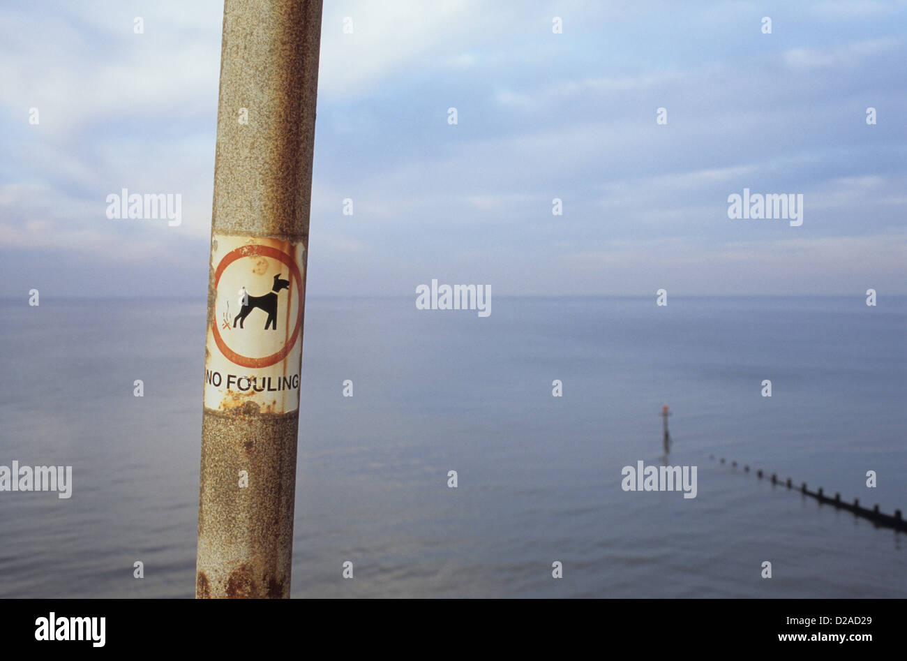 Arrugginimento palo in alluminio con preavviso con icona del cane indicando nessuna incrostazione di fronte calmo mare grigio sotto il cielo nuvoloso Foto Stock