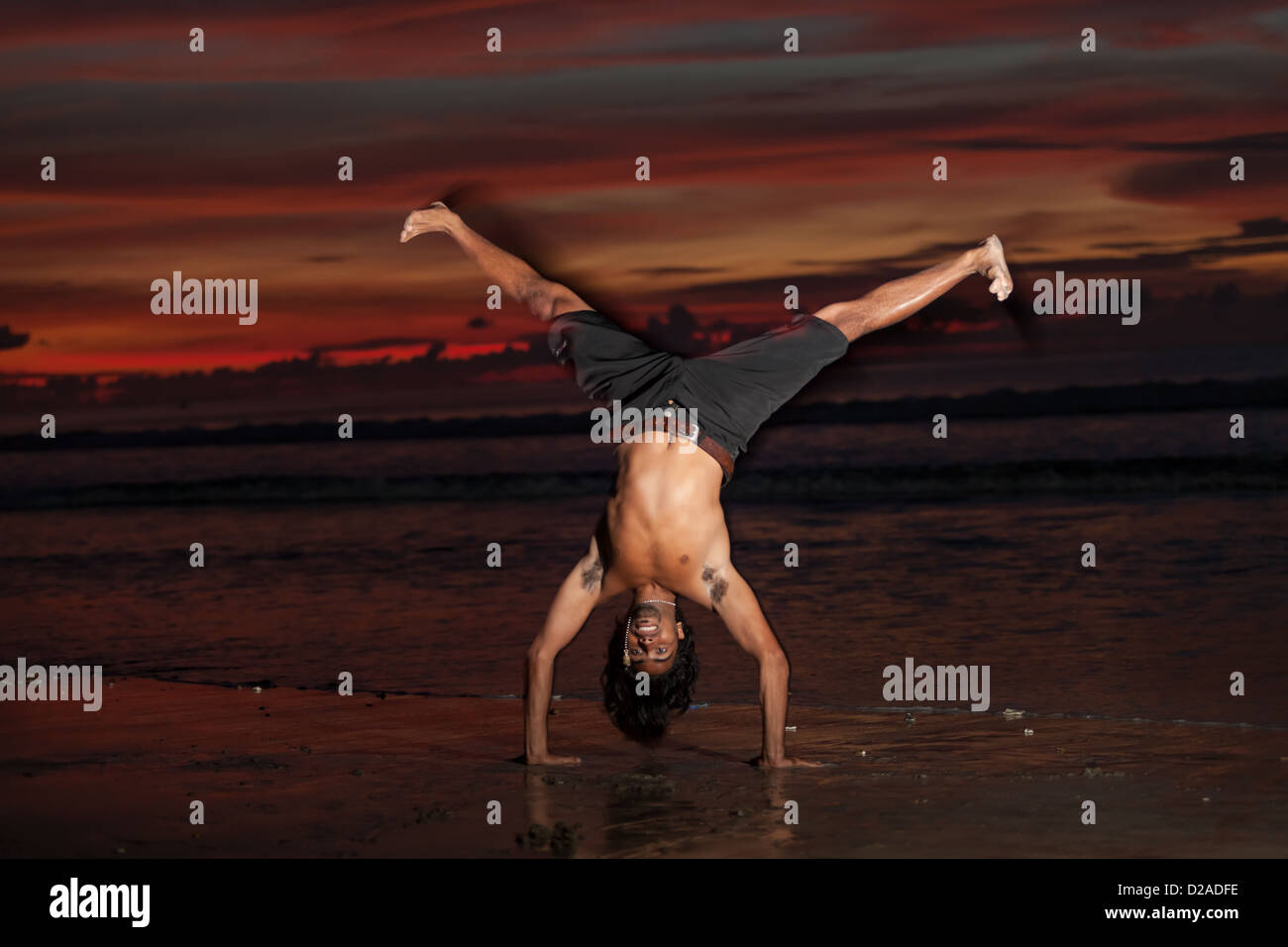 Giovane uomo facendo capoeira sulla spiaggia al tramonto Foto Stock