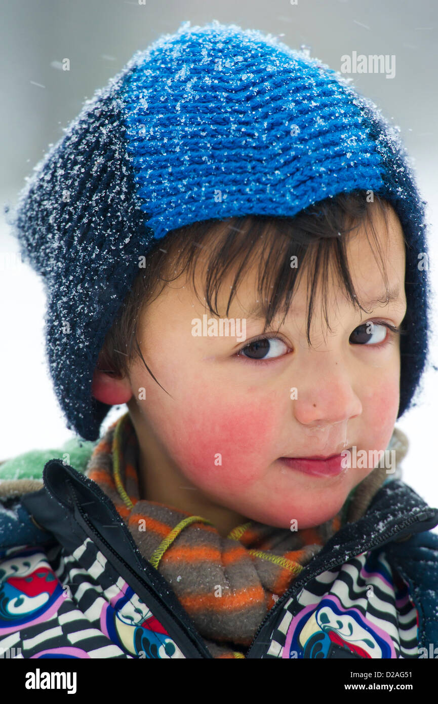 Calvino, di età compresa tra i 4, è rosey cheeked come egli gode la prima vera neve. Nevicata rende il pendolarismo più impegnativo ma non arresta dogwalkers o madri tenendo i loro bambini piccoli su Clapham Common, Londra, UK, 18 gennaio 2013. Foto Stock