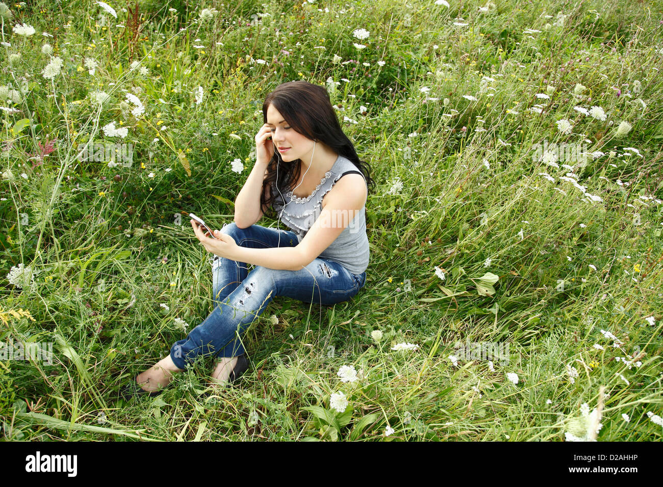 Donna ascoltando le cuffie in erba Foto Stock