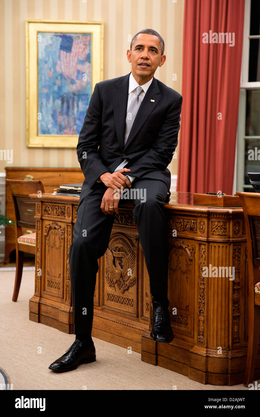 Il Presidente Usa Barack Obama si siede sul bordo della scrivania risoluto durante una riunione in ufficio Ovale della Casa Bianca 19 Dicembre 2012 a Washington, DC. Foto Stock