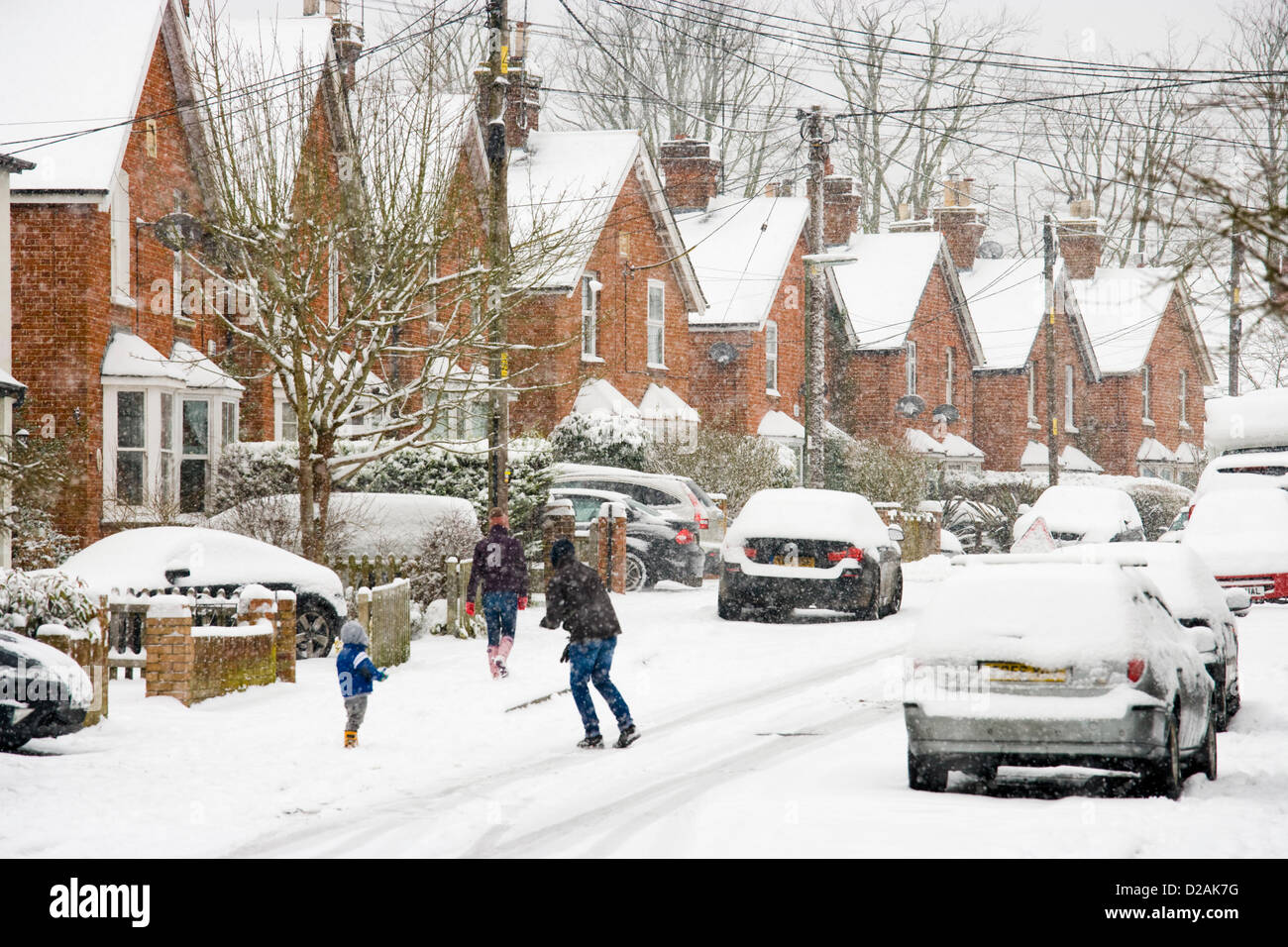 Persone in strada residenziale sotto la neve, Chobham, Surrey, Regno Unito. Foto Stock