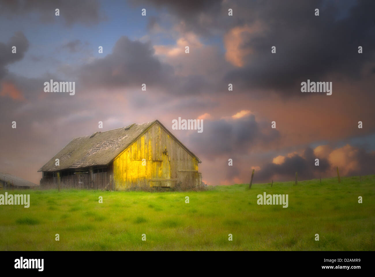Il vecchio fienile rustico in un campo sotto cieli bui con soft focus e illuminazione drammatica Foto Stock