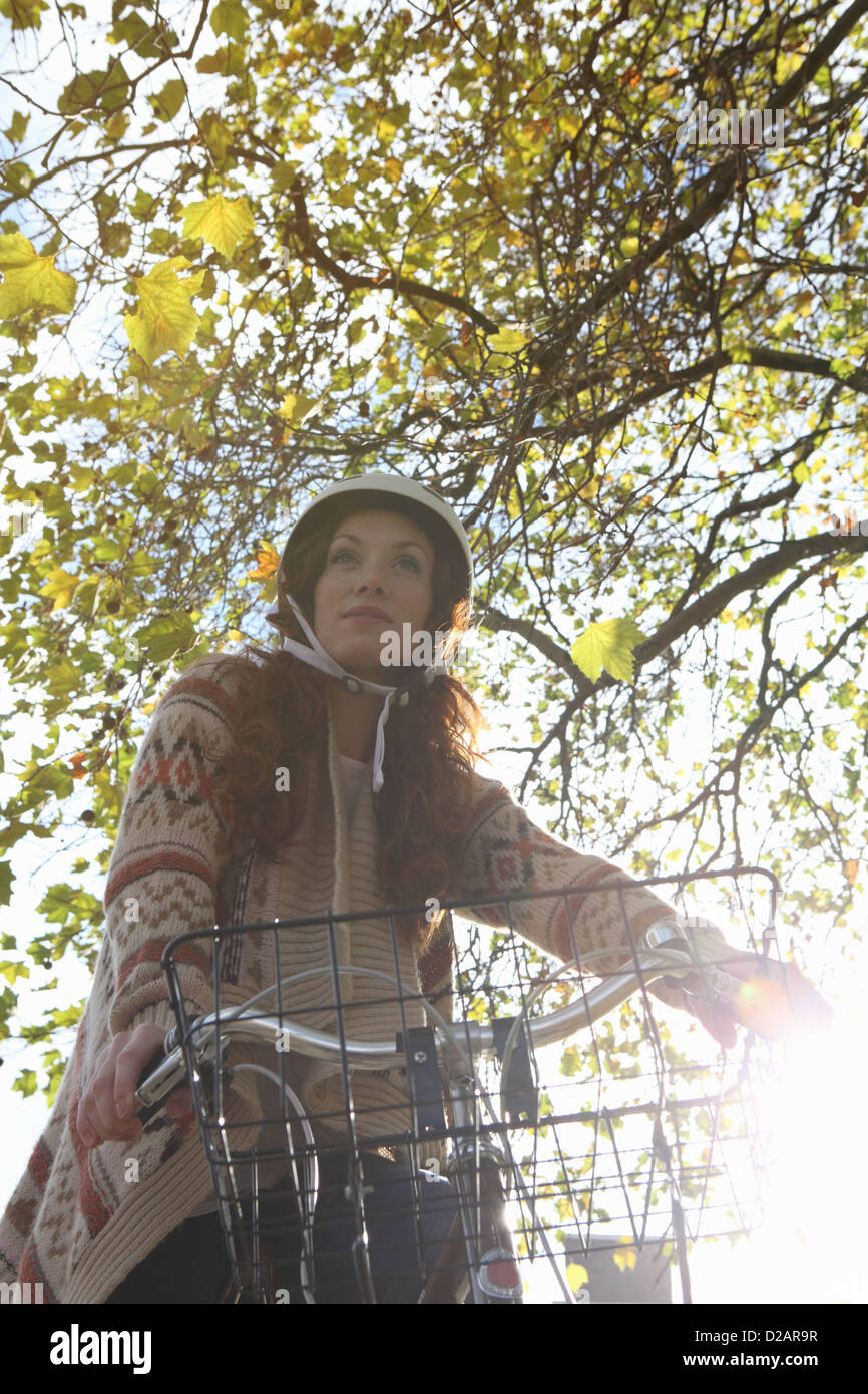 Donna in piedi con la bicicletta in posizione di parcheggio Foto Stock
