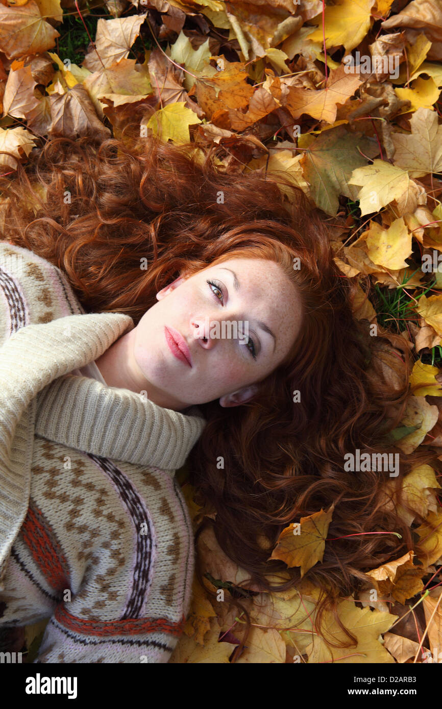 La donna posa in foglie di autunno Foto Stock