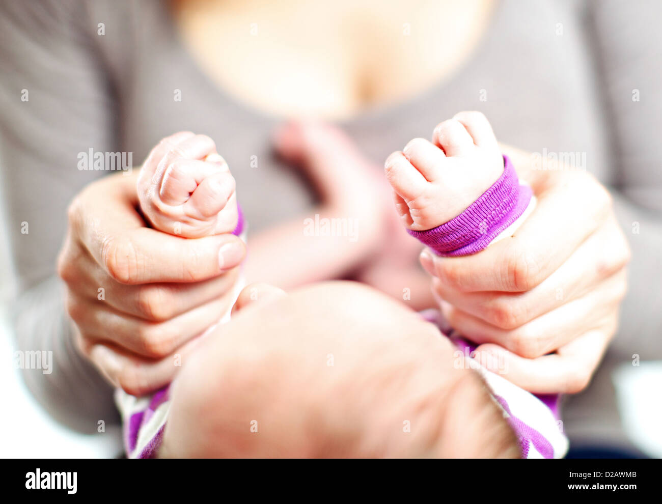 Overhead vista ritagliata di una madre tenendo un neonato con le mani in mano nel suo proprio con la messa a fuoco per le mani Foto Stock