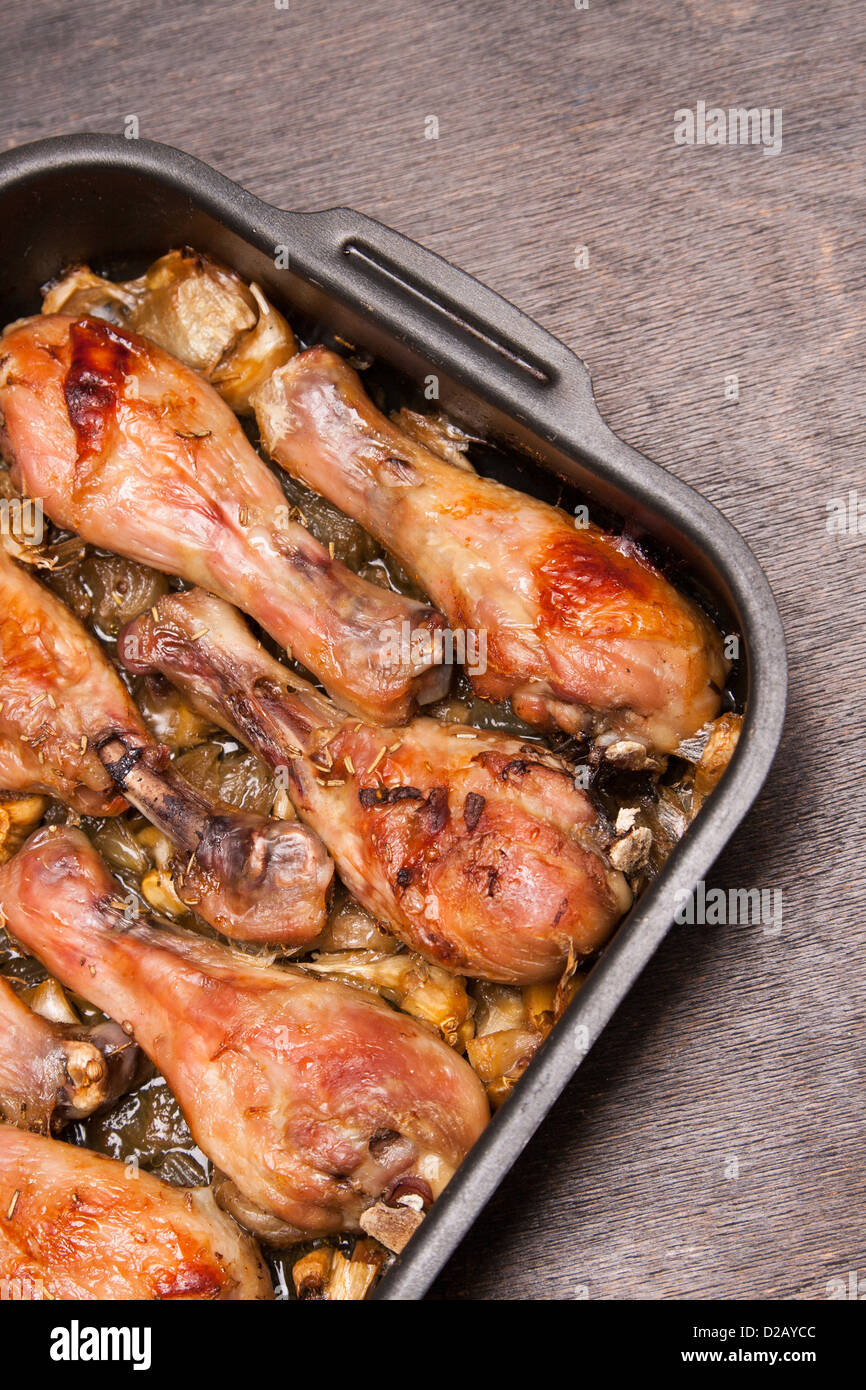 Cotte le cosce di pollo nel vassoio sul nero lo sfondo di legno Foto Stock