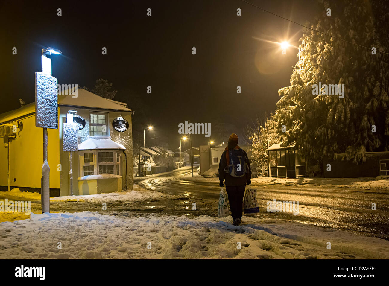 Una singola donna cammina a casa durante la notte nella neve portando il suo shopping da Abergavenny, Wales, Regno Unito Foto Stock Una singola donna cammina a casa durante la notte nella neve portando il suo shopping da Abergavenny, Wales, Regno Unito Foto Stock