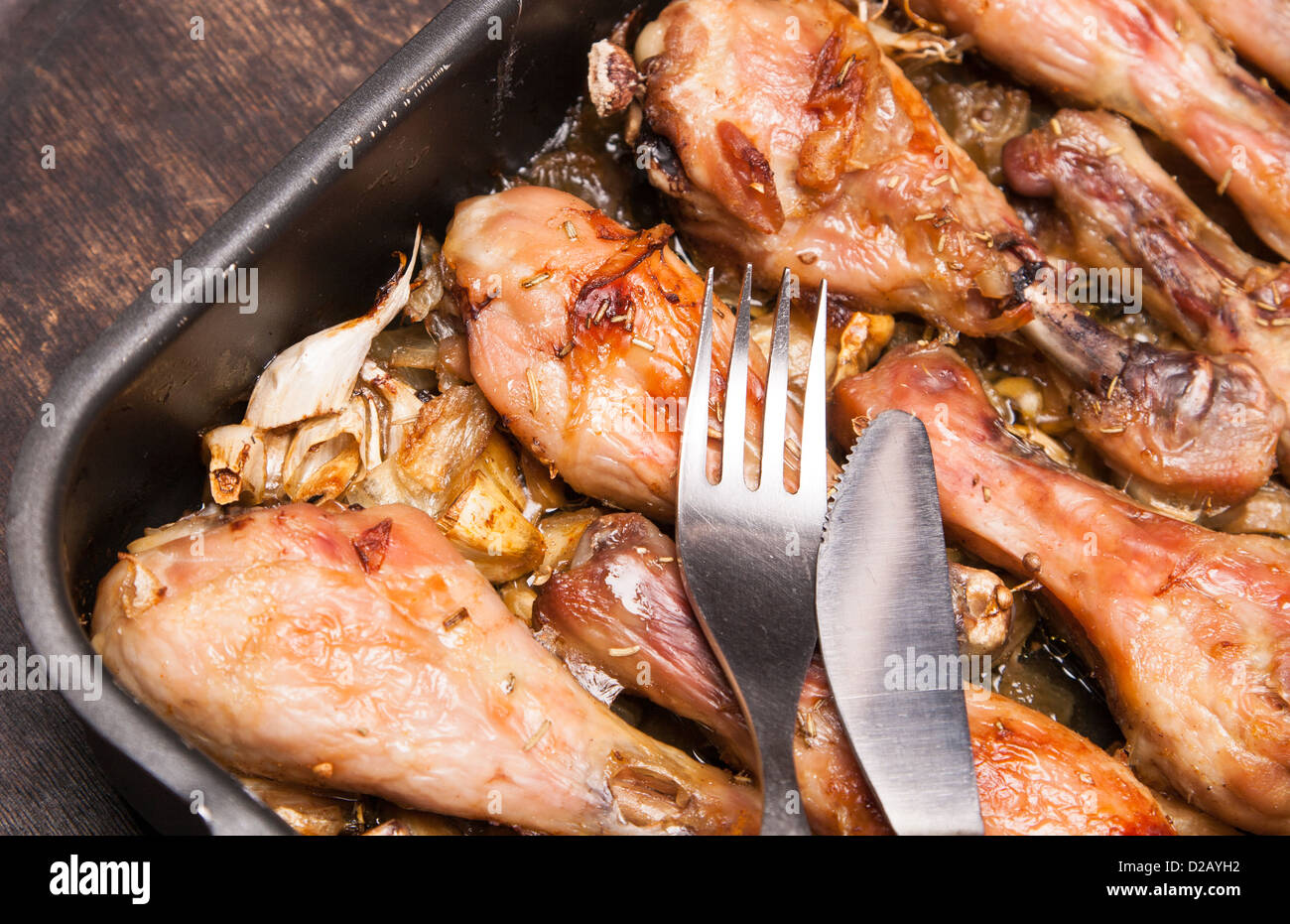 Cotte le cosce di pollo nel vassoio sul nero lo sfondo di legno Foto Stock