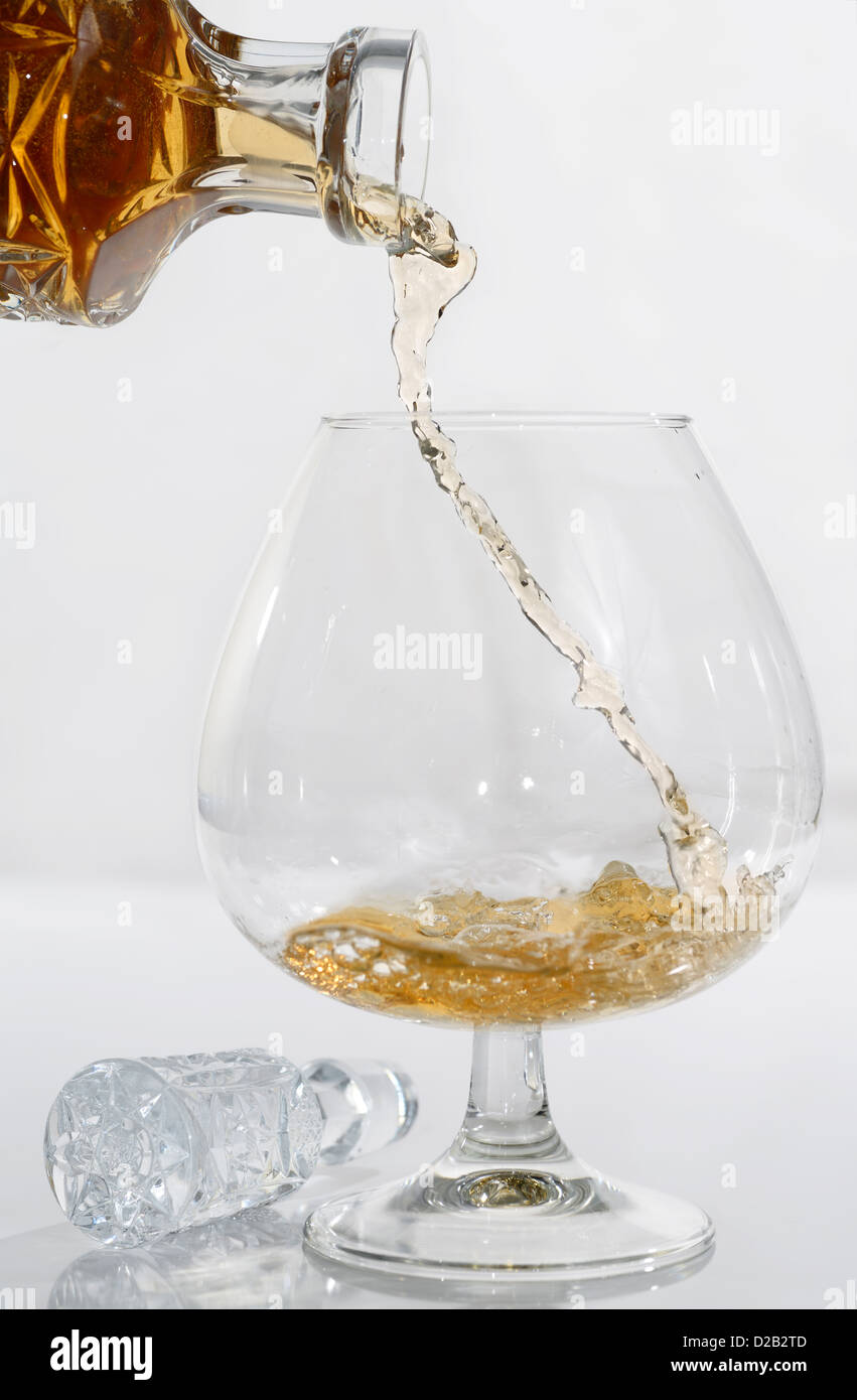 Alta velocità di flusso congelato il travaso di cognac versata in un brandy snifter su sfondo bianco Foto Stock