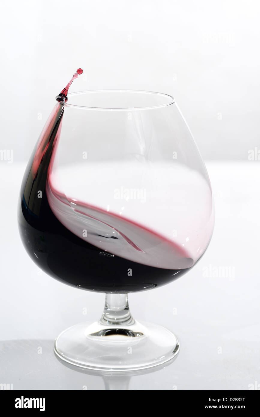 Porta di vorticazione schizzi fino al punto di caduta in sospensione in un bicchiere snifter su sfondo bianco Foto Stock Porta di vorticazione schizzi fino al punto di caduta in sospensione in un bicchiere snifter su sfondo bianco Foto Stock