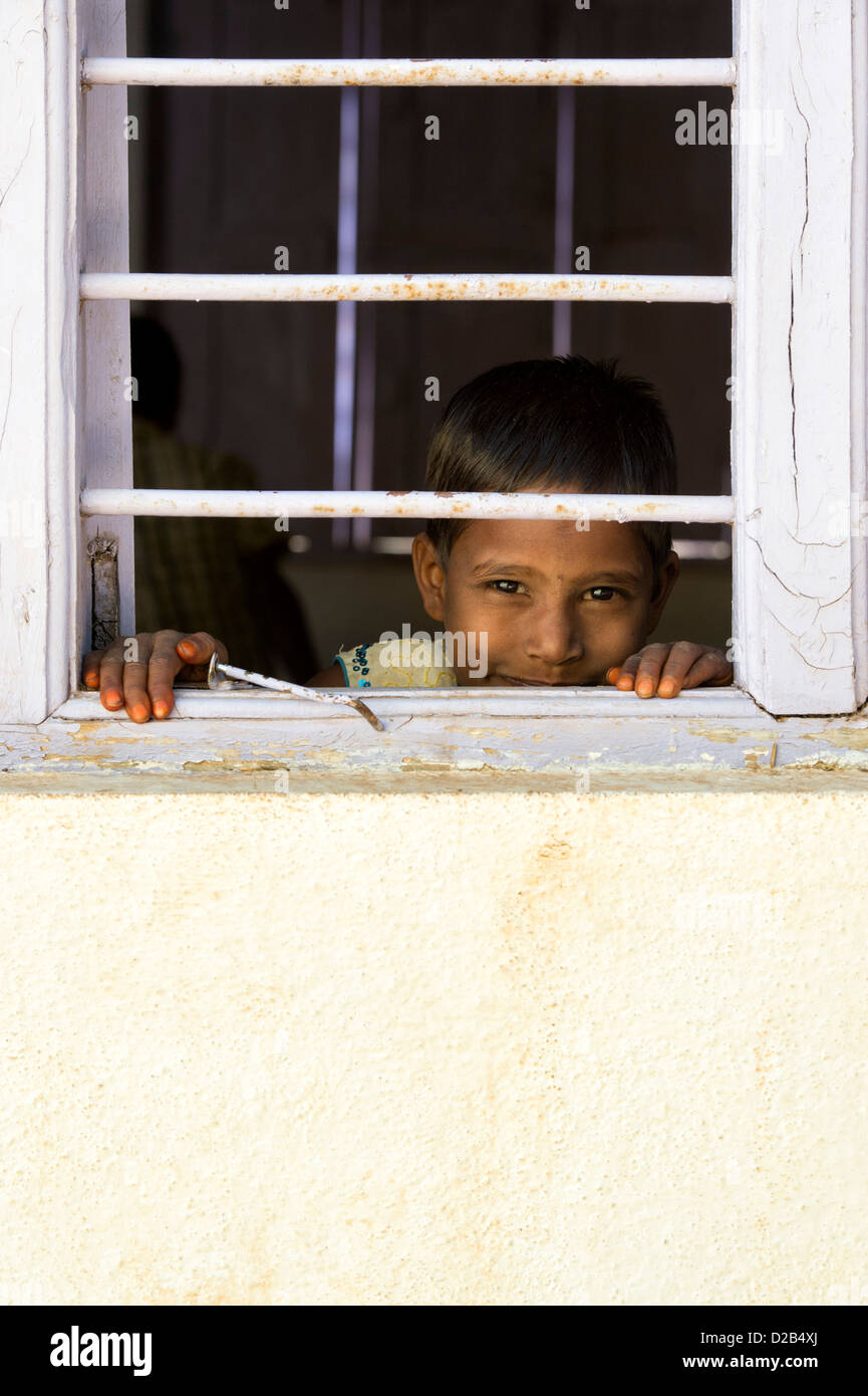 Giovani indiani i bambini del villaggio guardando attraverso la finestrella barre in una casa indiana. Andhra Pradesh, India Foto Stock