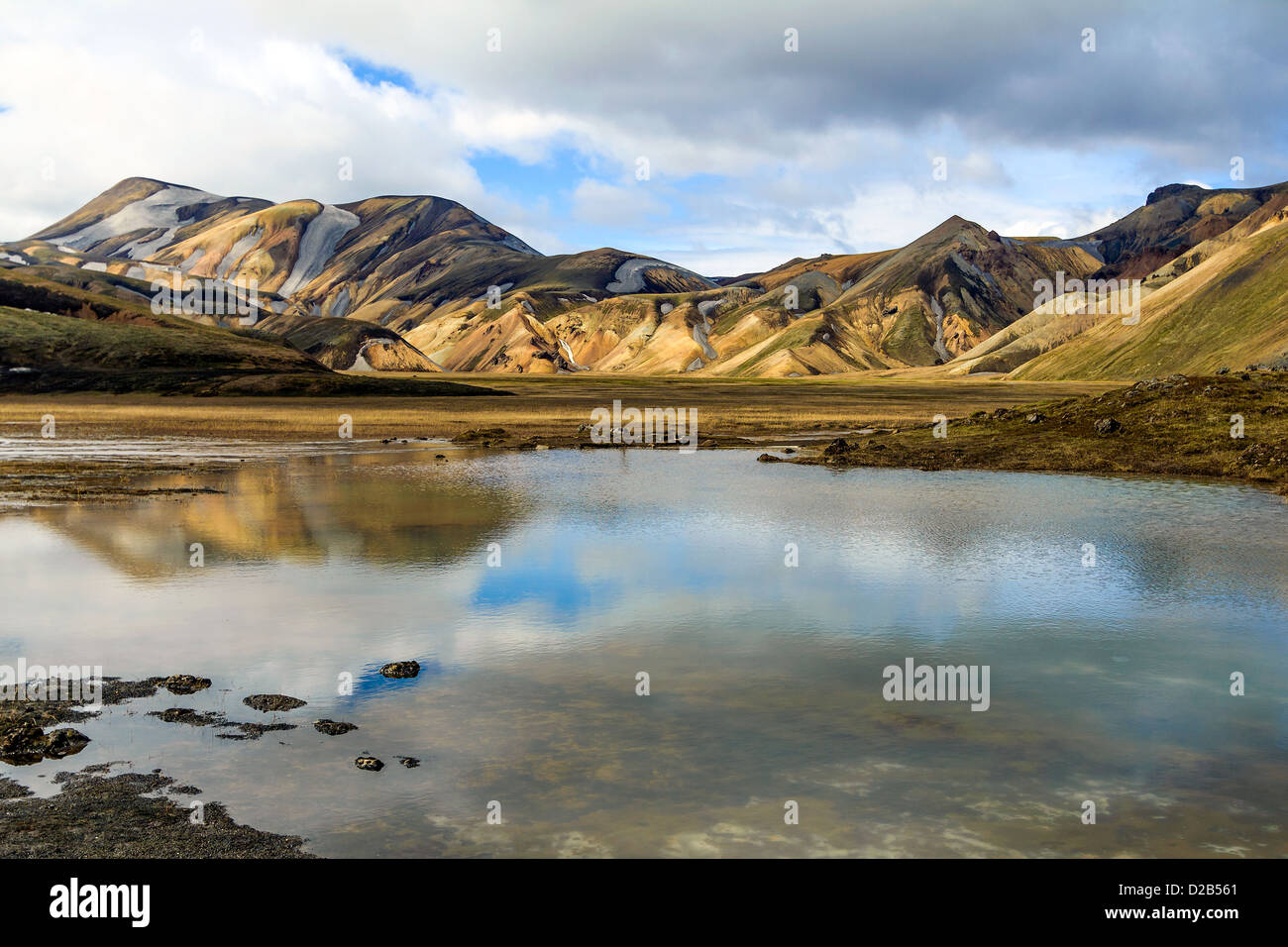 La roccia arcobaleno di Landmannalaugar si riflette ancora in un lago sotto un cielo nuvoloso, Islanda. Foto Stock