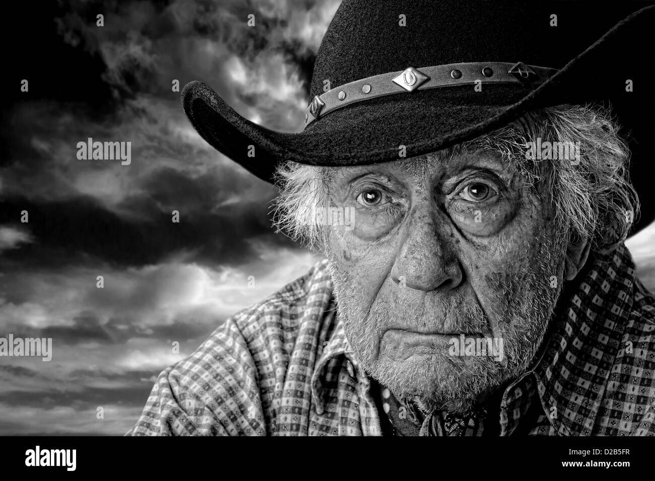 Monocromatica di un vecchio uomo che indossa un cappello in feltro nero contro un burrascoso cielo nuvoloso Foto Stock