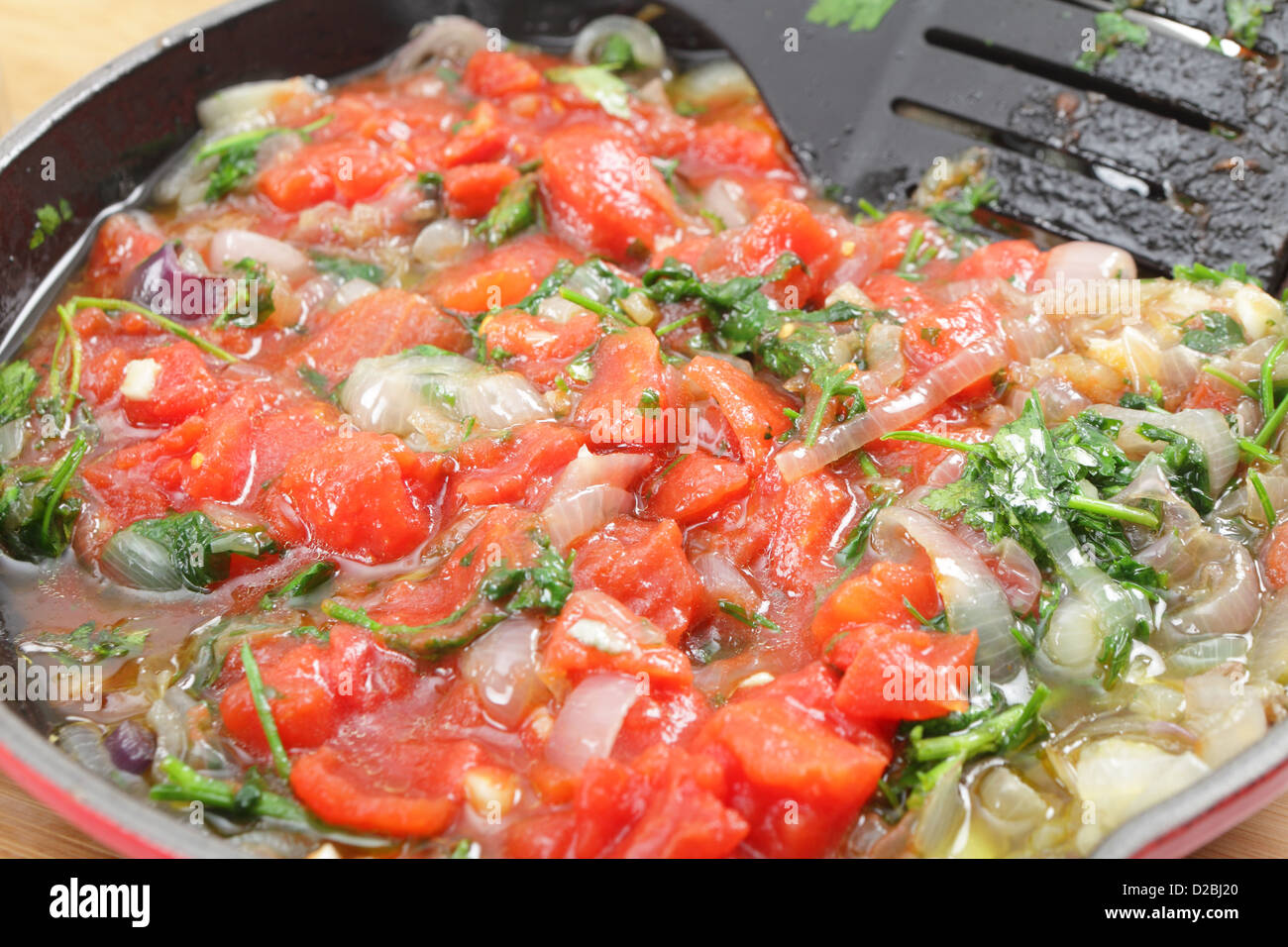 Cipolla fritti e il prezzemolo e i pomodori in una padella, preparazione per un greco di melanzane ripiene piatto, Imam Baildi o Imam melitzanes Foto Stock