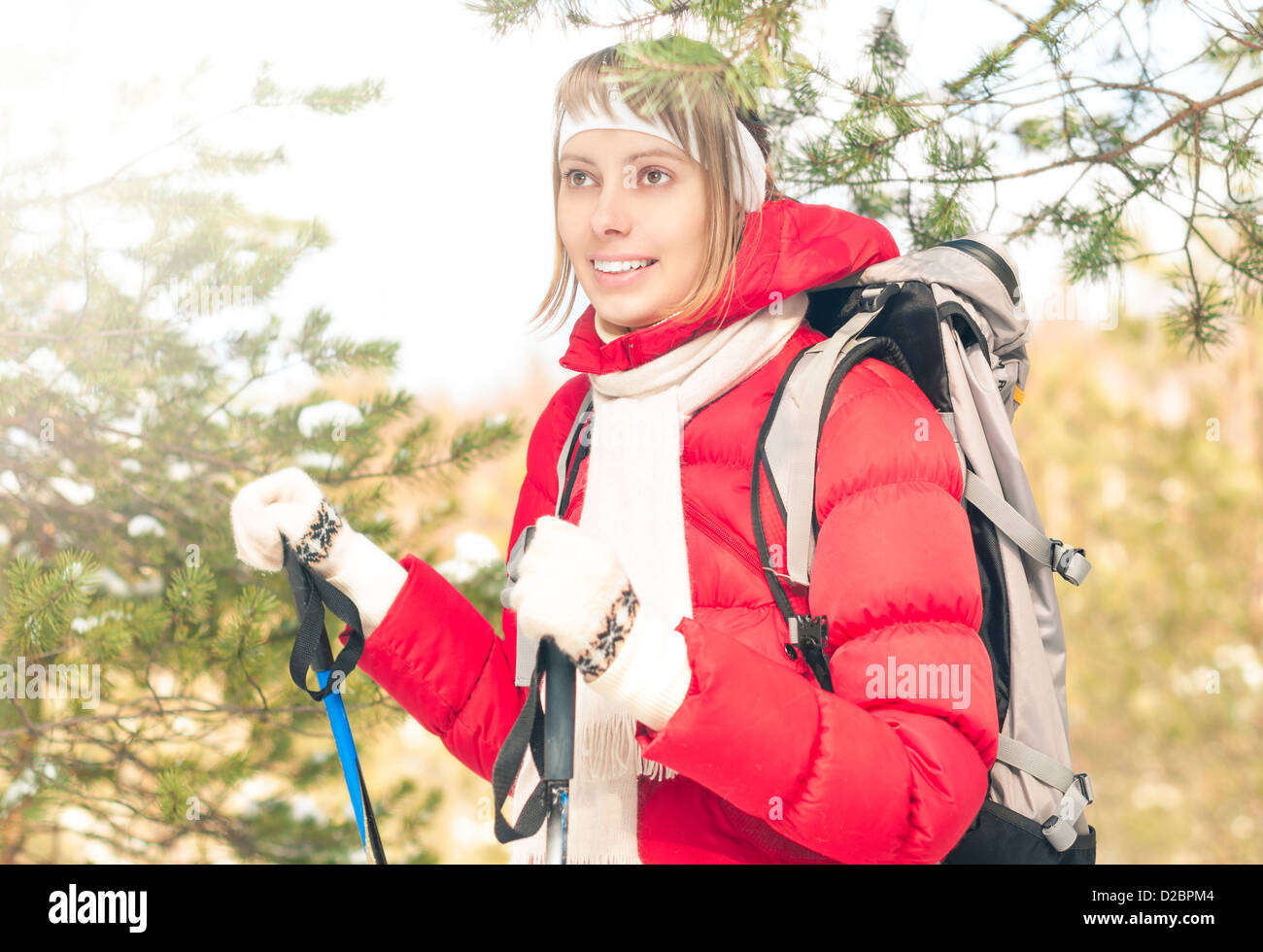 Bella ragazza in camicia rossa in piedi con zaino e bastoncini da sci. Sorridenti donna gode luminoso giorno d'inverno. Inverno nevoso fo Foto Stock