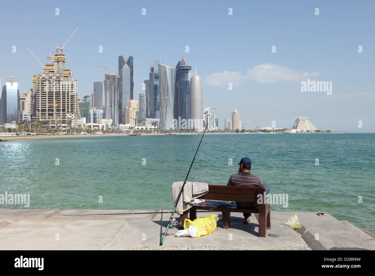 Un asiatico expat a Doha, in Qatar, si gode il suo sabato la pesca dalla Corniche nella baia di Doha Foto Stock