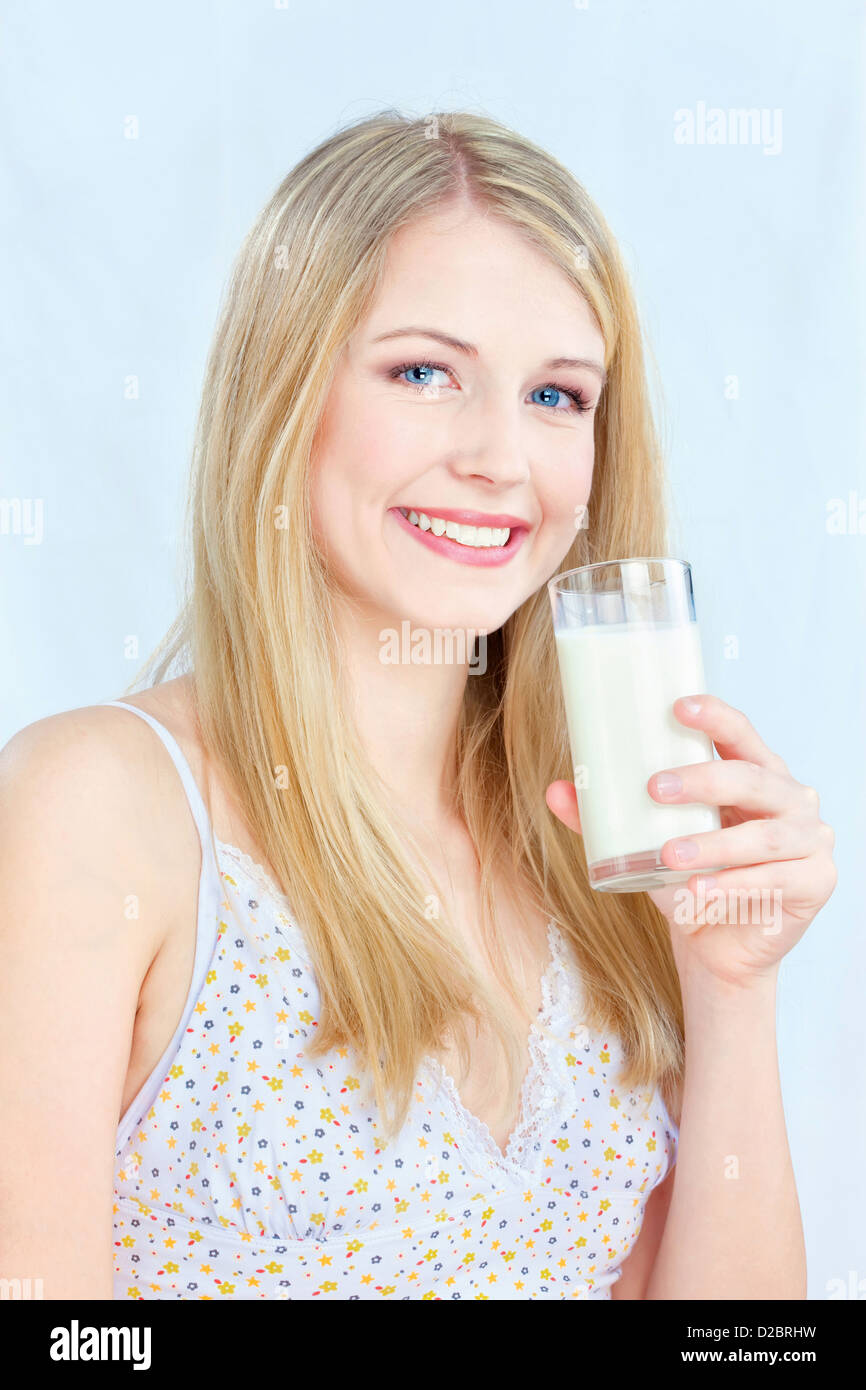Felice capelli biondi donna tenendo un bicchiere di latte Foto Stock