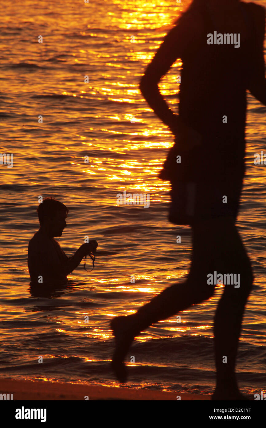 Nuotatore avente un inizio di mattina dip come un pareggiatore passa durante il sunrise a Sydney la famosa Bondi Beach in una ondata di caldo giorno. Foto Stock