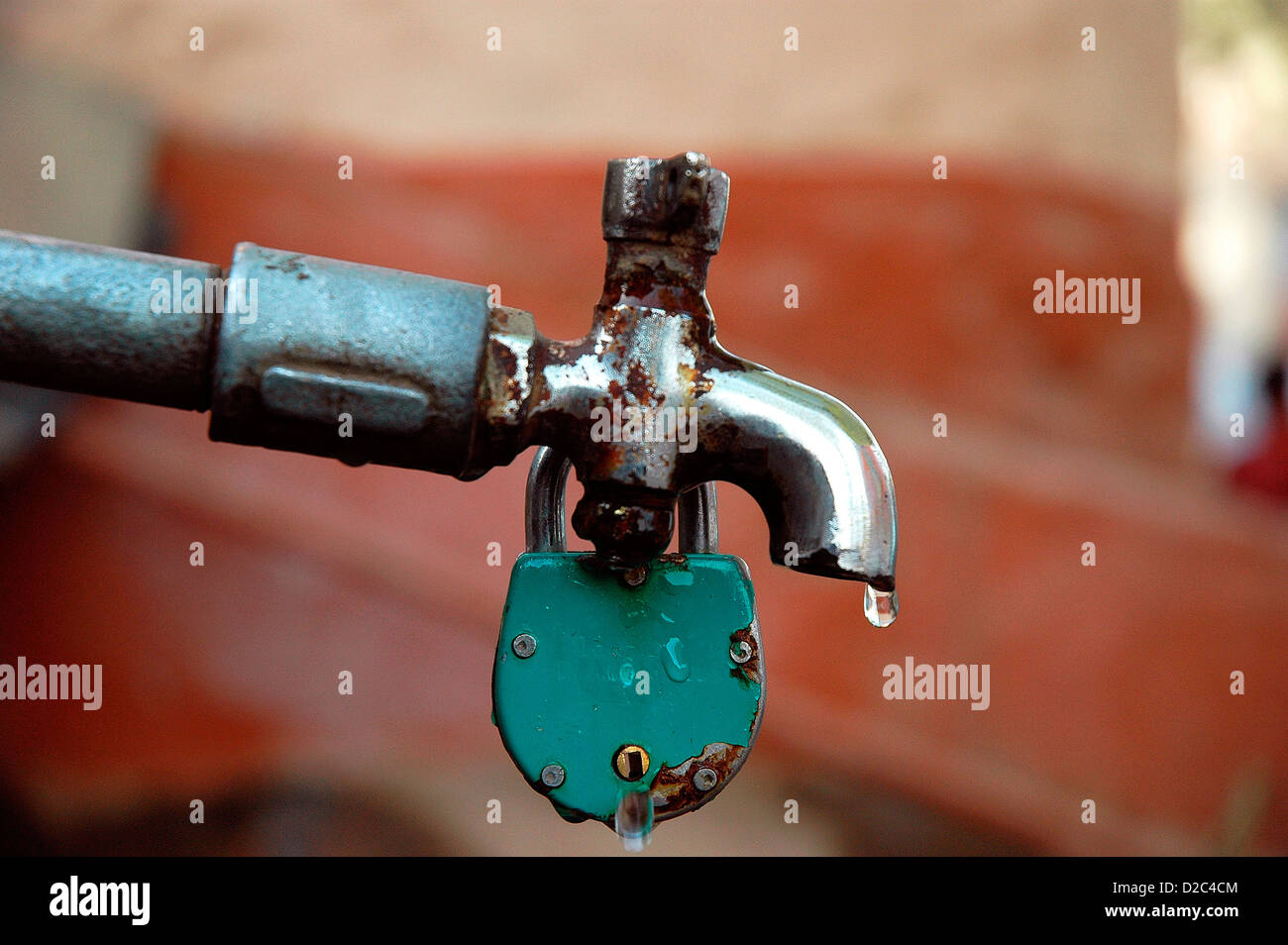 Una sola goccia di acqua che gocciola fuori tocca chiuso con una serratura Foto Stock