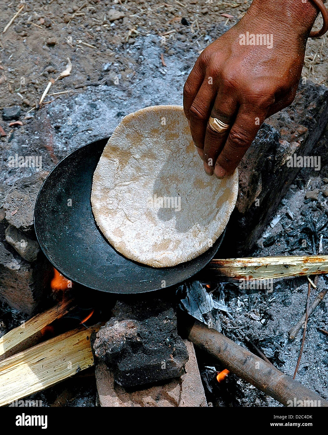 Indian uomo pellegrino per la cottura del pane di frumento Roti sulla tradizionale fuoco di legno Foto Stock