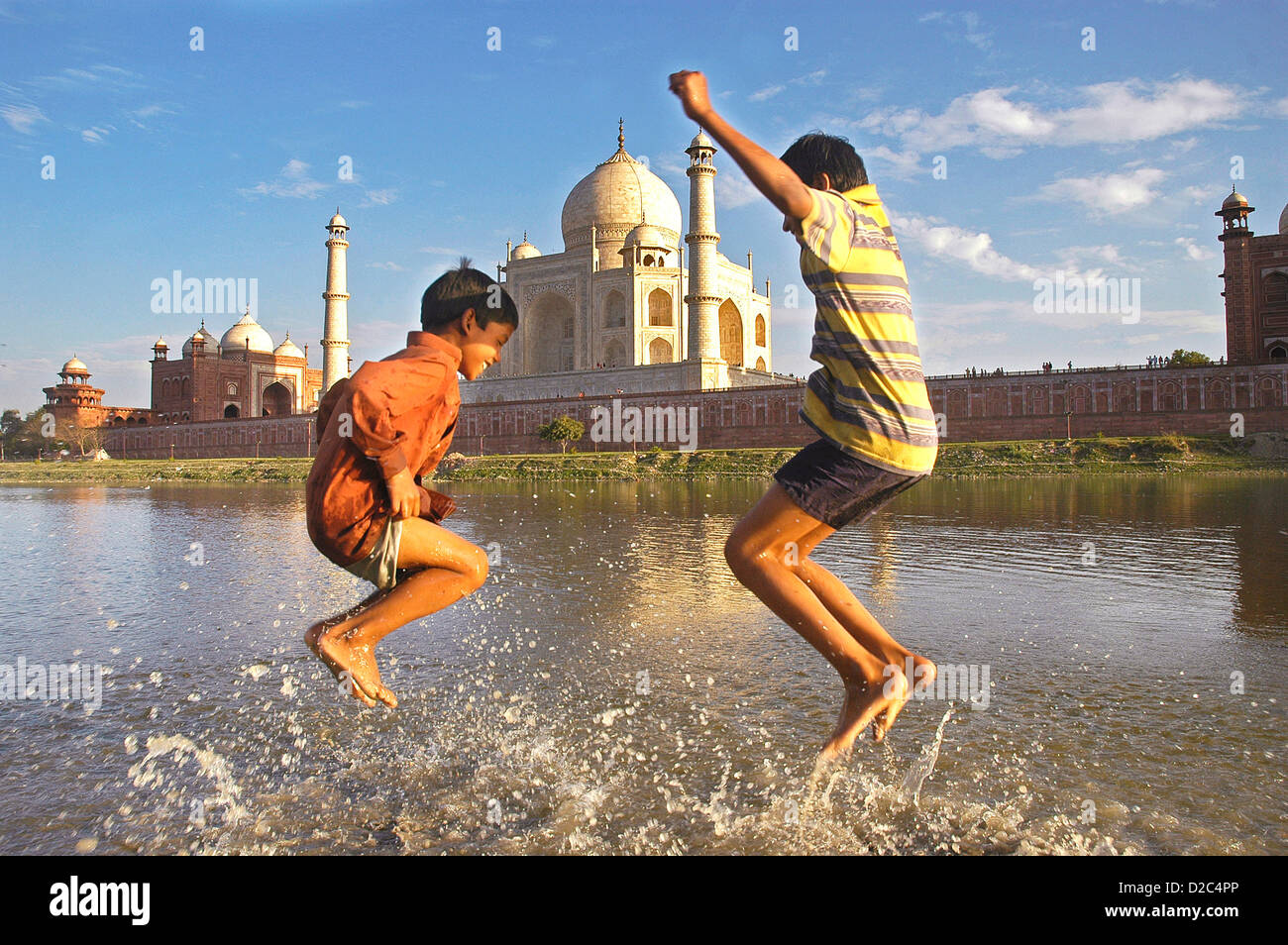 Due bambini che giocano in acqua di fiume Yamuna che fluisce oltre il Taj Mahal , Agra, Delhi, India Foto Stock