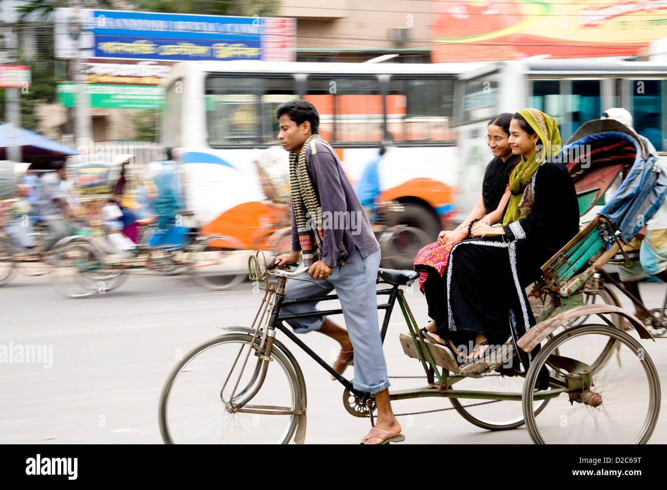 Cycle Rickshaw cavaliere a cavallo con i passeggeri. Dacca in Bangladesh Foto Stock