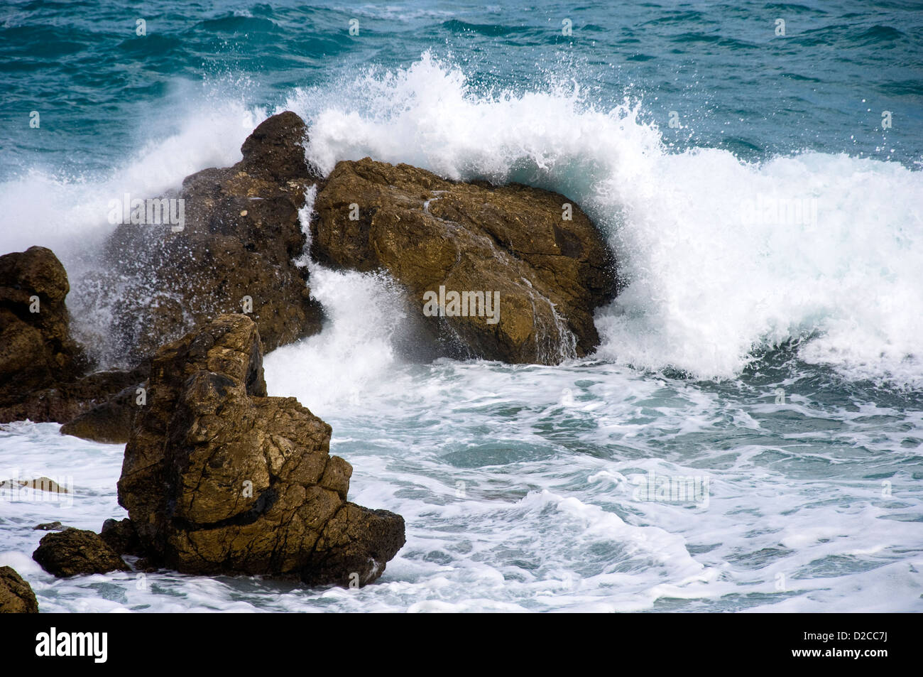 Wave si infrangono sulla spiaggia rocciosa Foto Stock