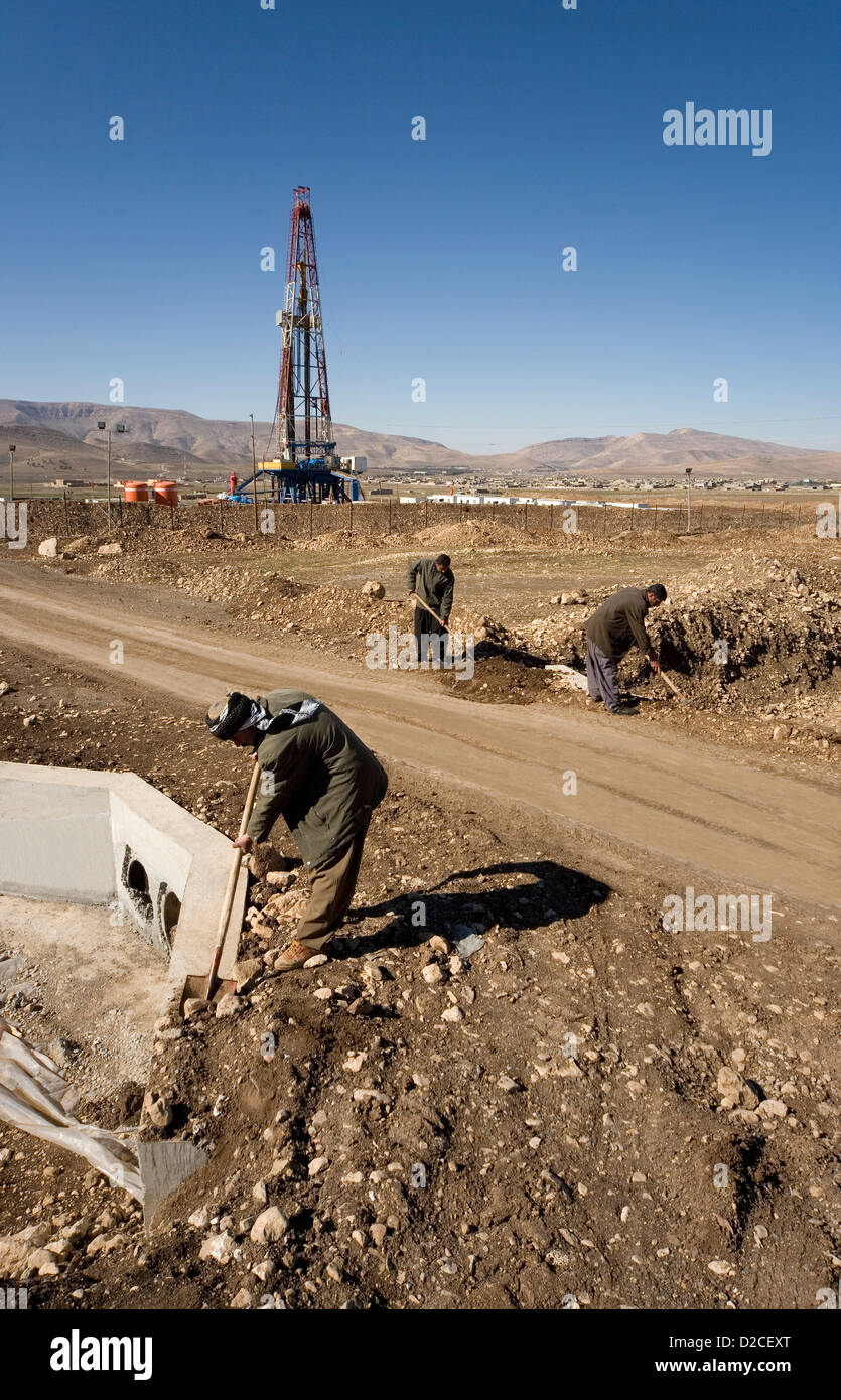 Onshore di esplorazione di petrolio e gas rig sito piattaforma e curdi iracheni dal villaggio locale impiegato per il trasporto su strada e su canale sotterraneo iraq kurdistan Foto Stock