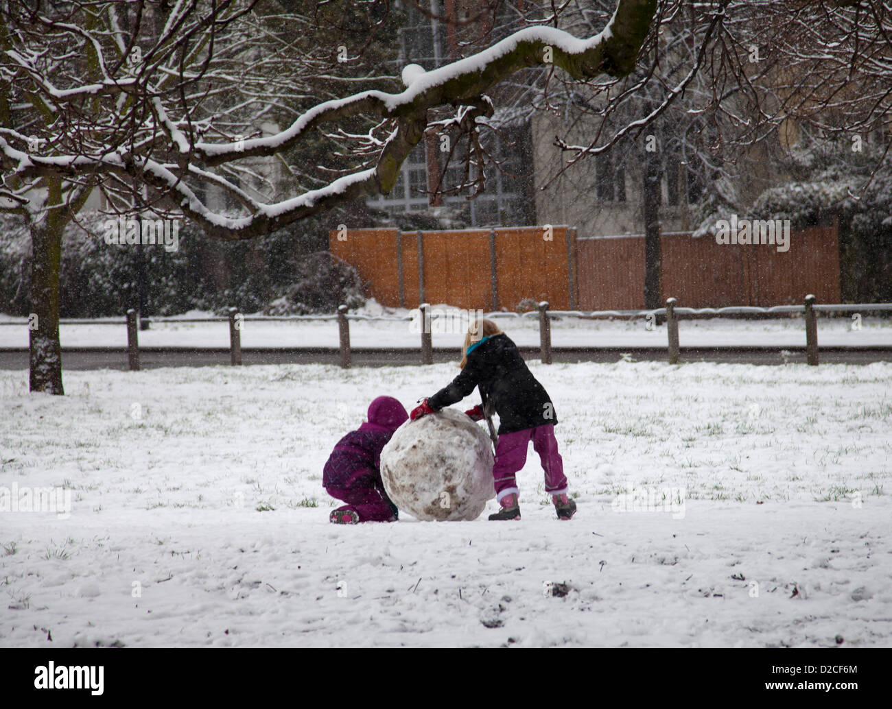 20 gennaio 2013 13,18 pm - La neve cade su Clapham Common a Clapham, Londra, Regno Unito. due giovani bambini facendo rotolare una palla di neve Foto Stock