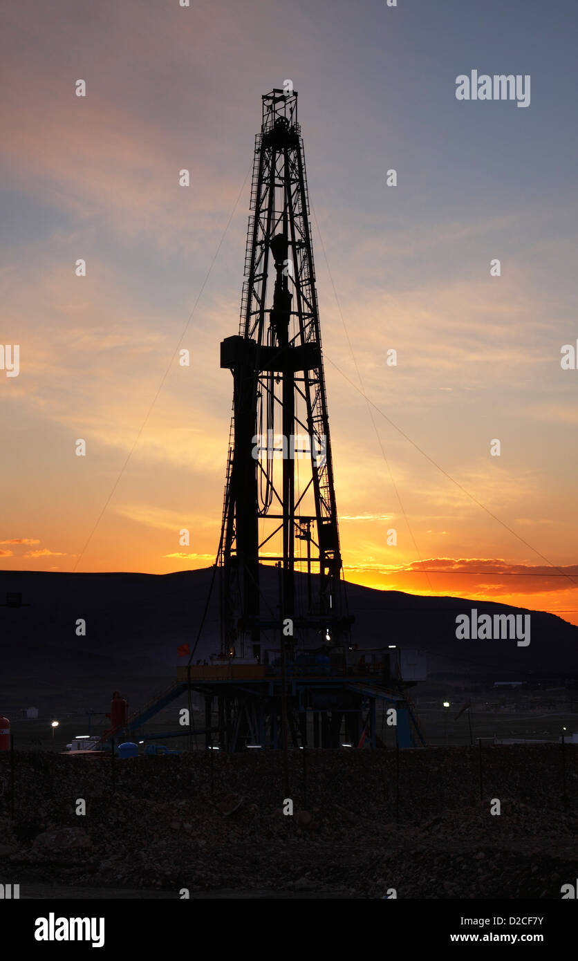 Olio e gas esplorazione onshore rig derrick al tramonto con le montagne dietro. Il Kurdistan iracheno, Iraq settentrionale Foto Stock