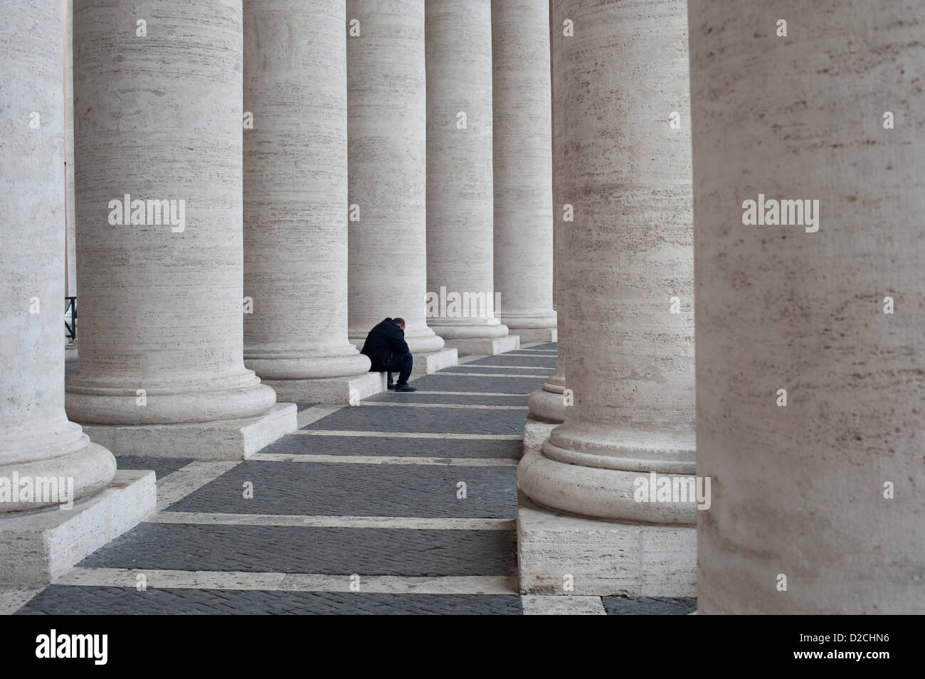 Uomo seduto in colonnato di Piazza San Pietro. Foto Stock