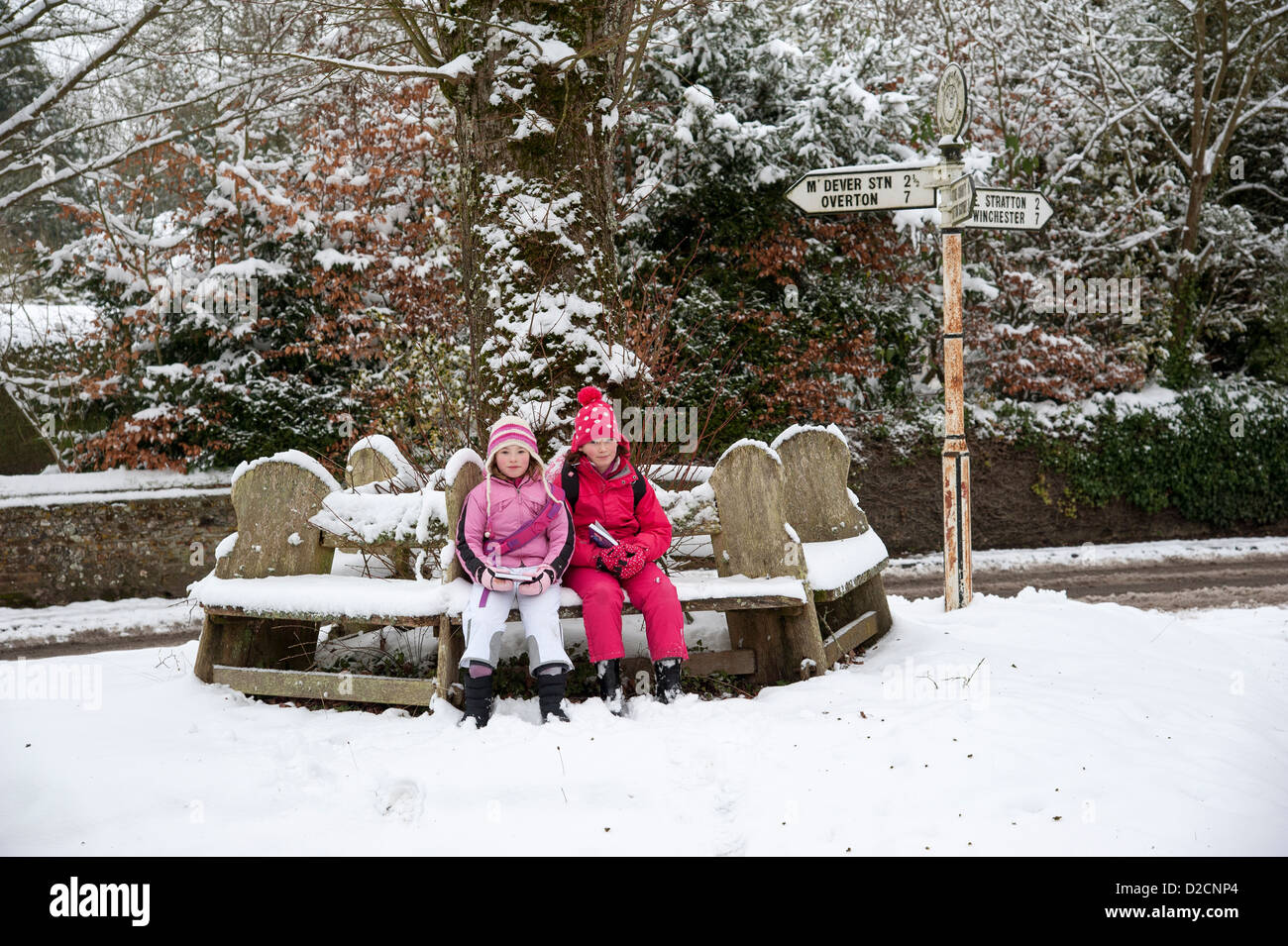 Micheldever un villaggio rurale in Hampshire REGNO UNITO Inghilterra durante l'inverno bambini seduti su un comune panca in legno Foto Stock