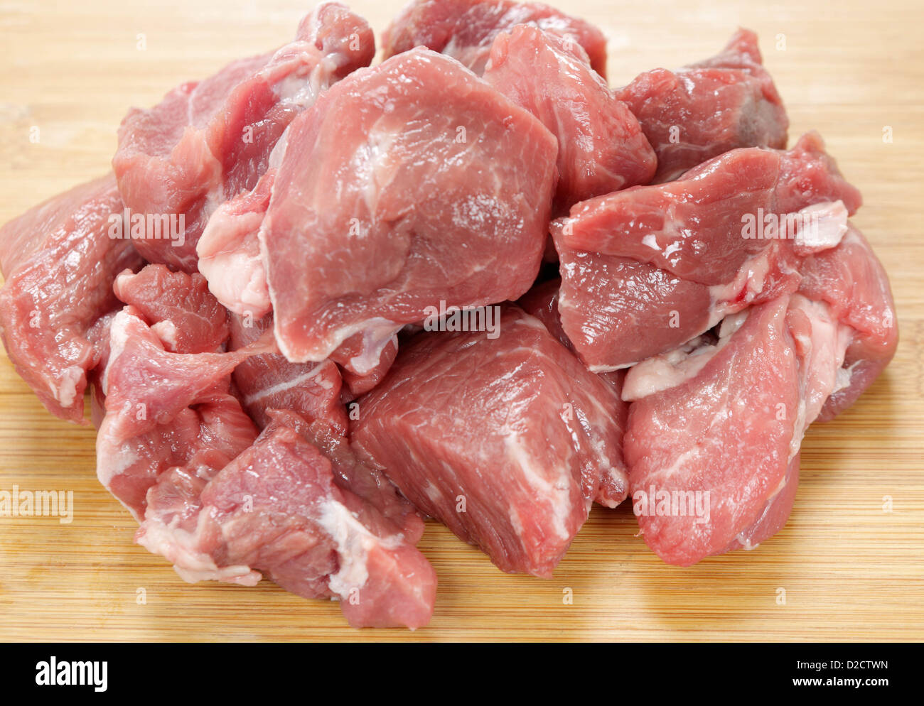 Carne di agnello, tagliato in cubetti ruvida, su un tagliere di legno Foto Stock