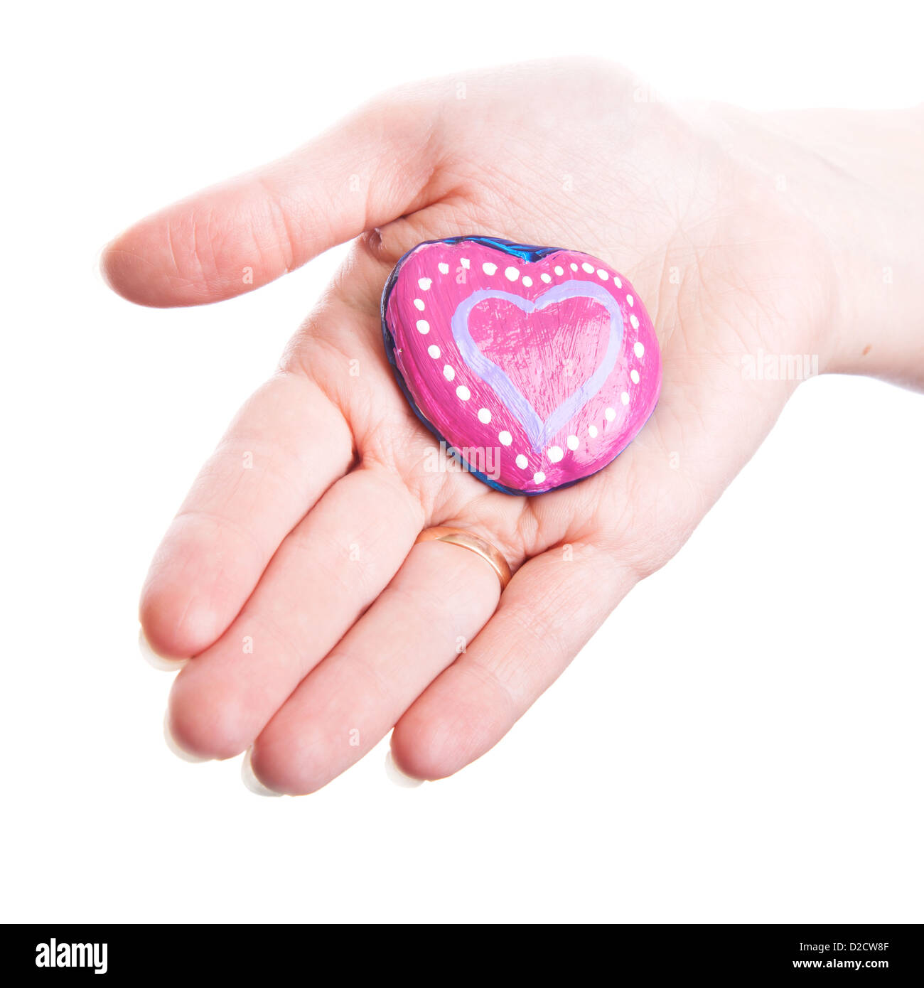 Rosa dipinta a mano a forma di cuore di pietra come un dono nella donna la mano isolato su bianco Foto Stock