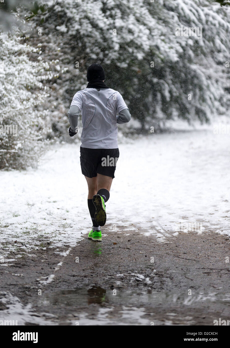 Un pareggiatore indossando scarpe verde, sfidando la neve in inverno nel Parco di Chiswick House Foto Stock