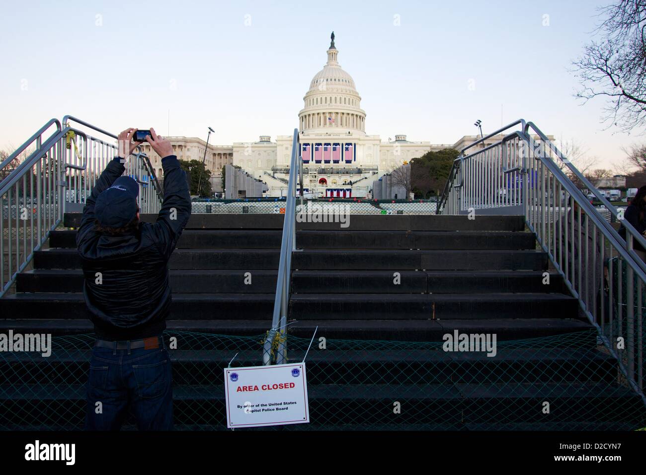 Gennaio 20, 2013, Washington DC. Un uomo prende una foto dell'U.S. Capitol da una barriera in una zona sicura. Sebbene la 57th cerimonia inaugurale è domani, il Presidente Obama è stato giurato in questa mattina a causa di una disposizione costituzionale che i presidenti essere giurato in prima di mezzogiorno il 20 gennaio. Foto Stock