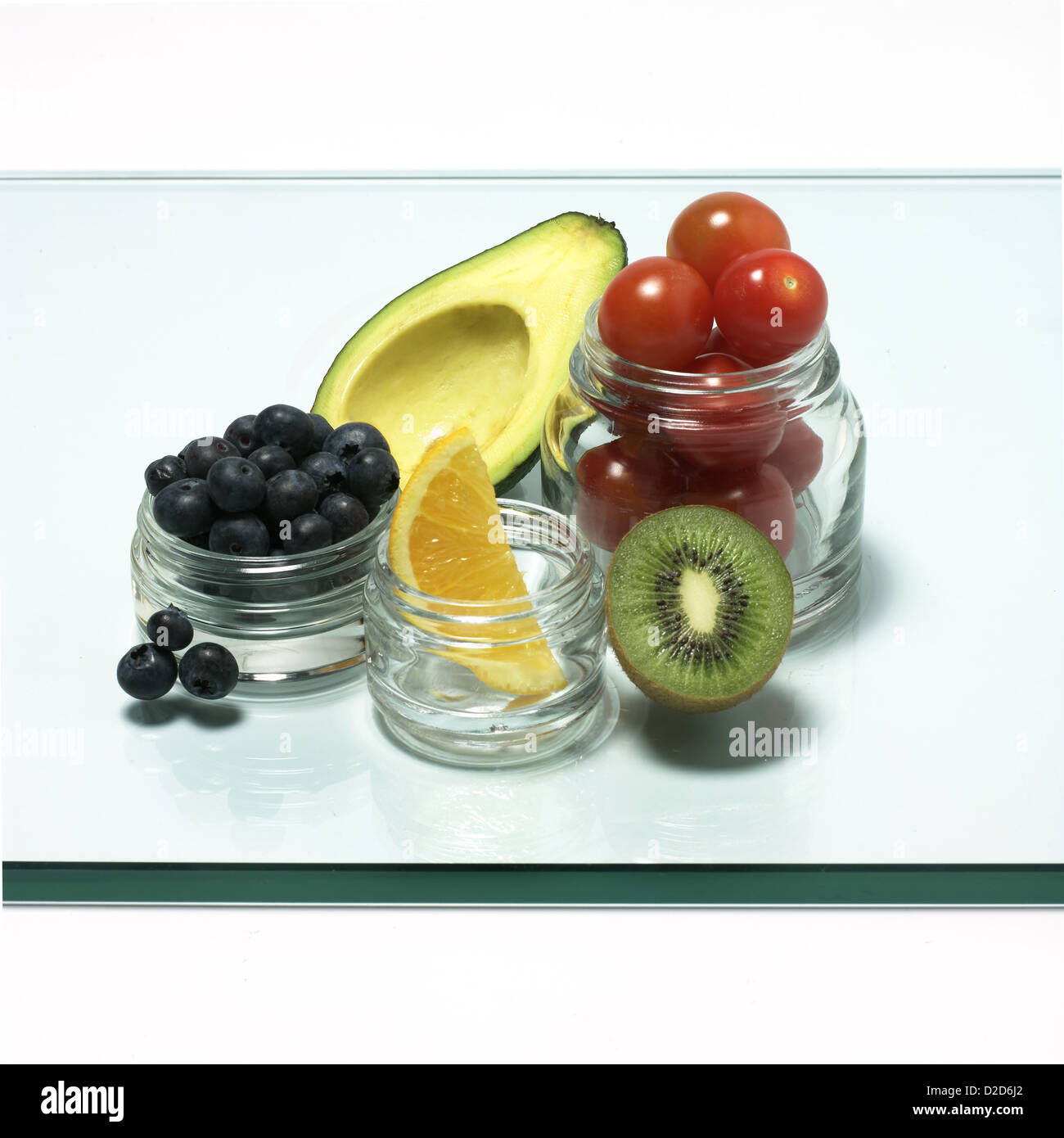 Selezione di frutta e verdura poste in vasi di vetro tagliato su sfondo bianco Foto Stock