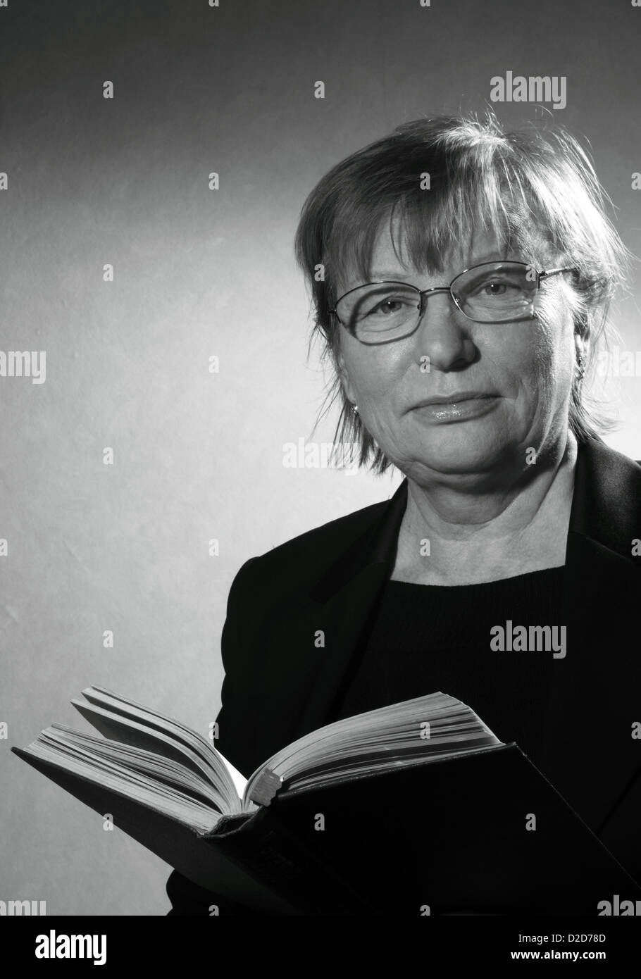 Bianco e nero ritratto di donna di mezza età in occhiali con libro Foto Stock