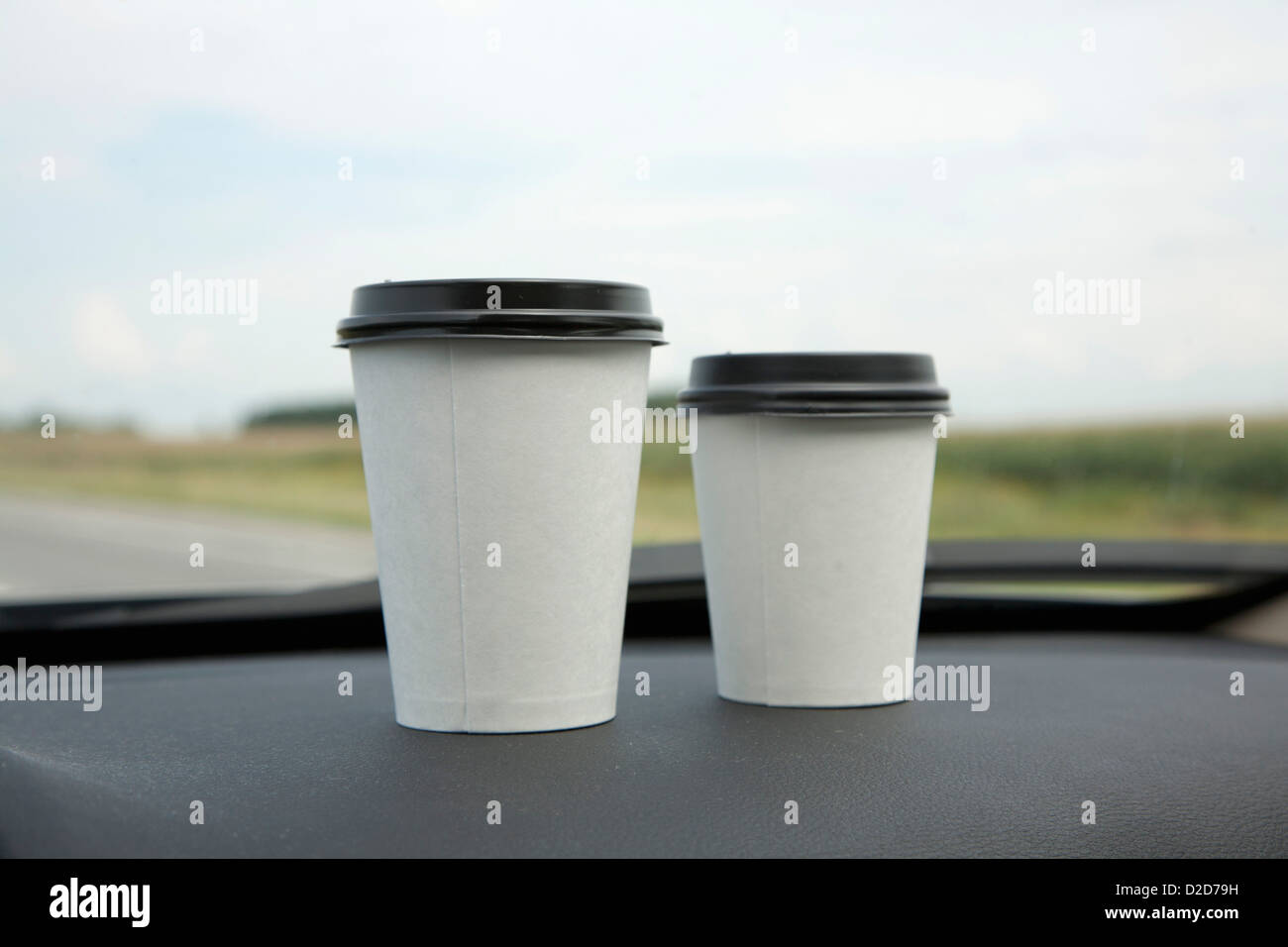 Due tazze monouso di caffè su un cruscotto di automobile Foto Stock