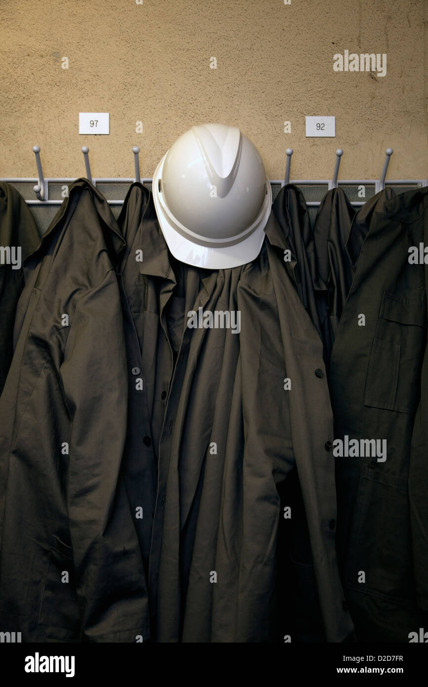Un elmetto e uniformi appeso su ganci Foto Stock
