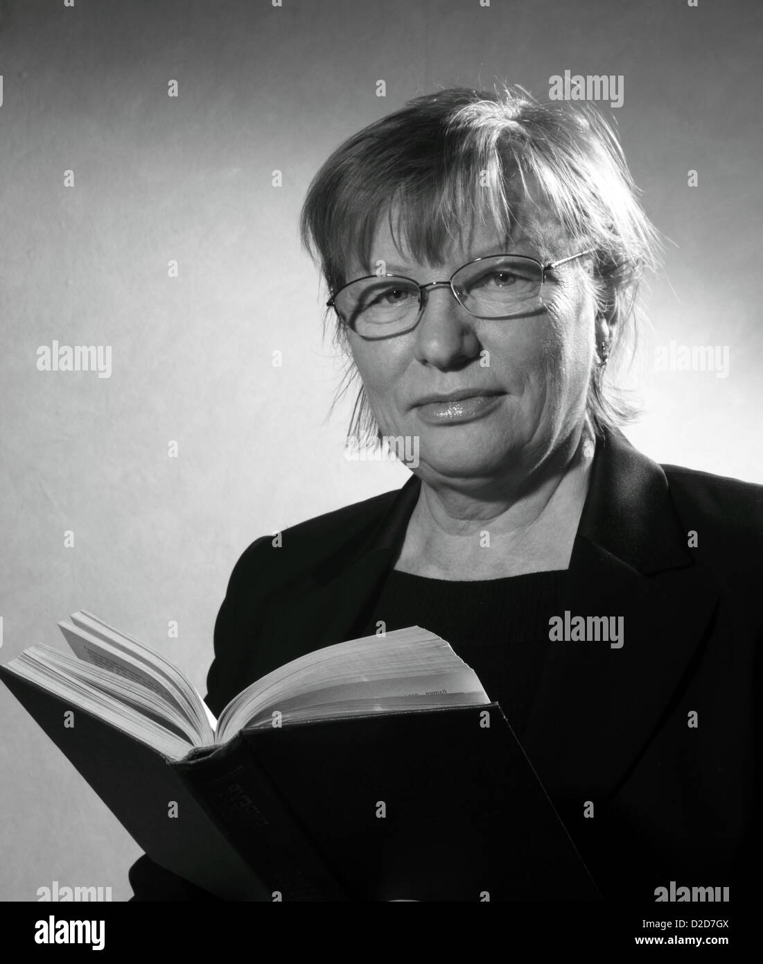 Bianco e nero ritratto di donna di mezza età in occhiali con libro Foto Stock